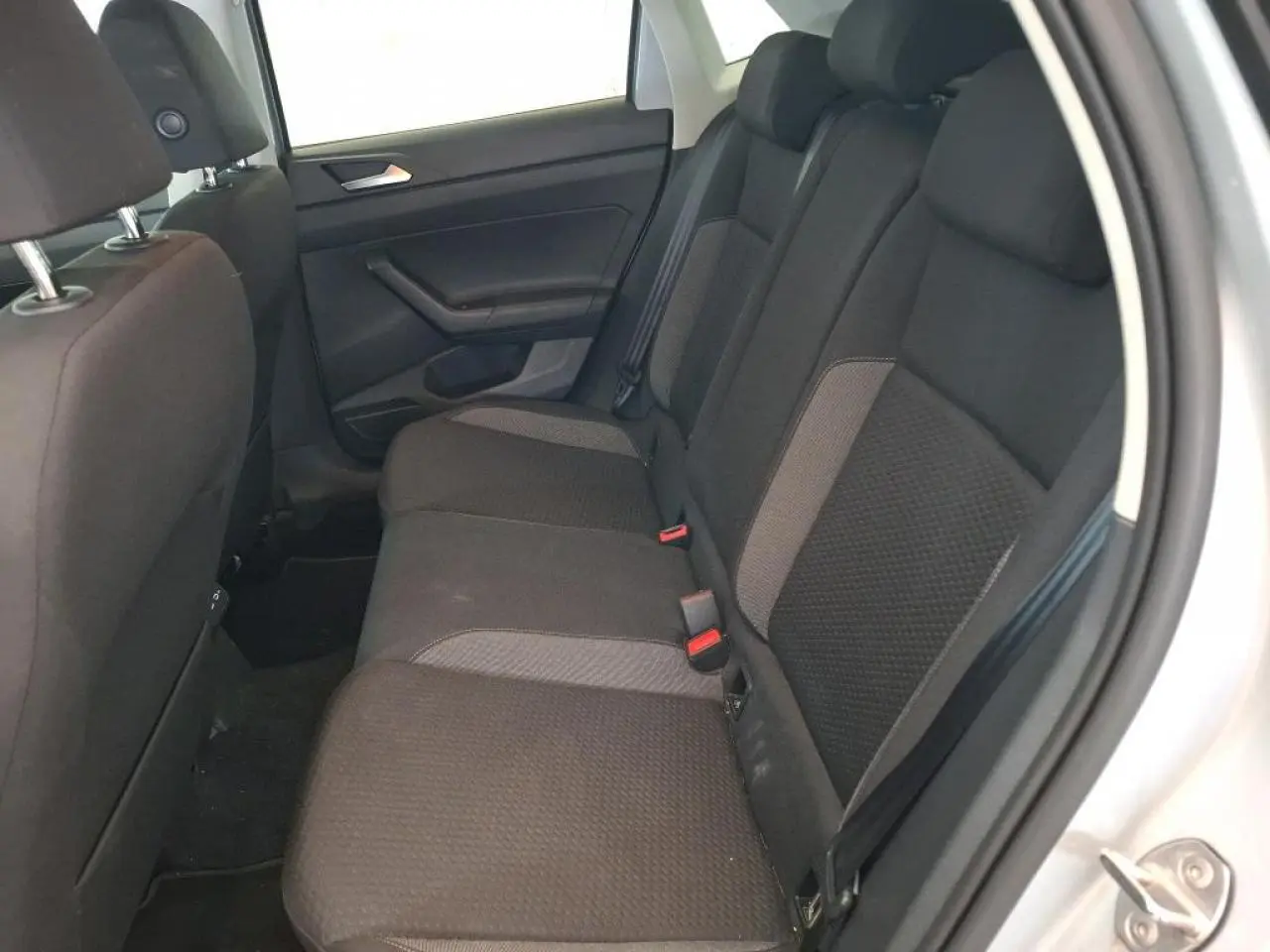 Vue intérieure côté droit de la banquette arrière en tissu gris foncé de la Volkswagen Polo 2024 gris clair.