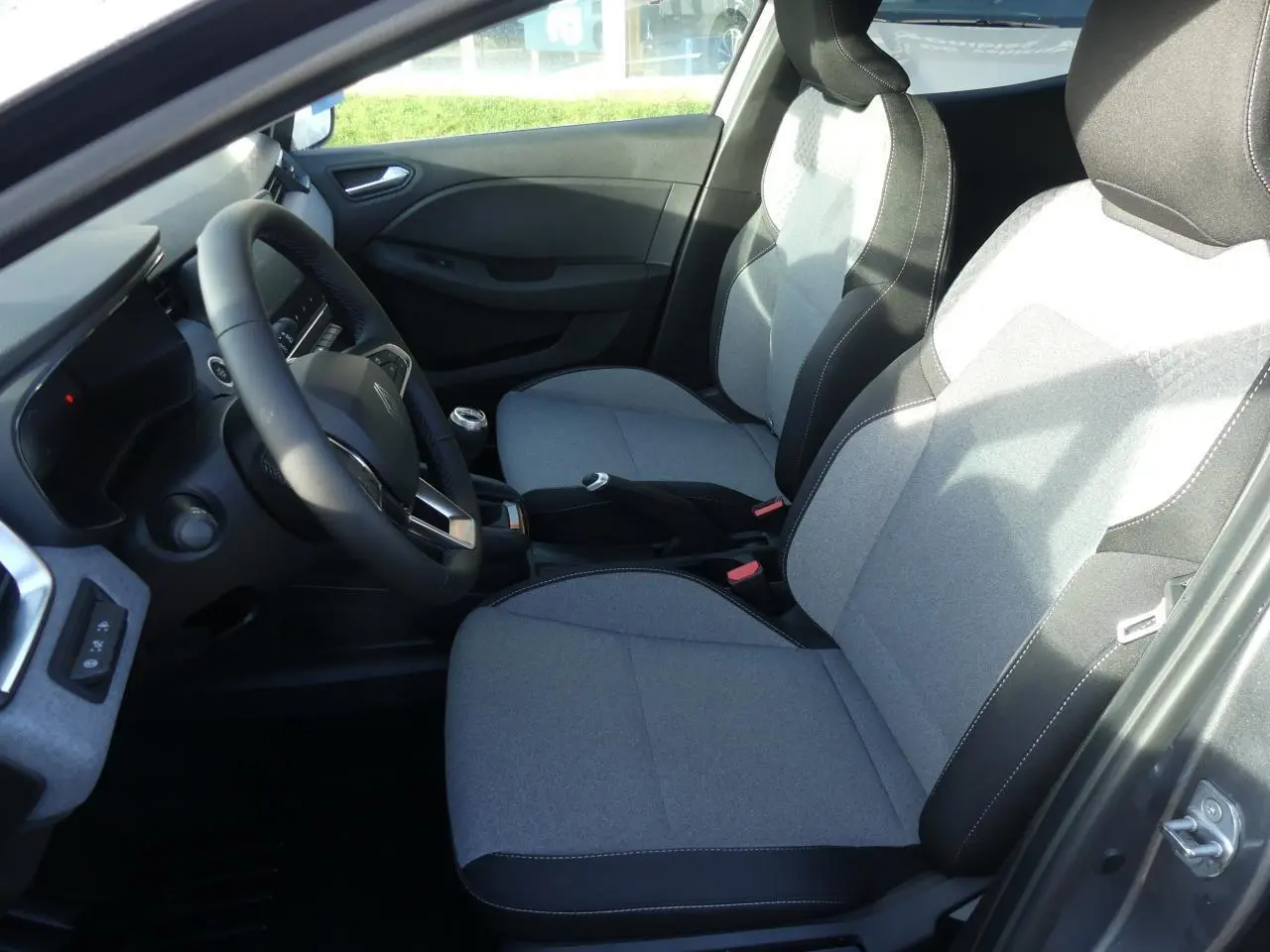 Vue intérieure côté conducteur de la Renault Clio gris schiste 2025, sièges tissu gris à motifs 3D twida.