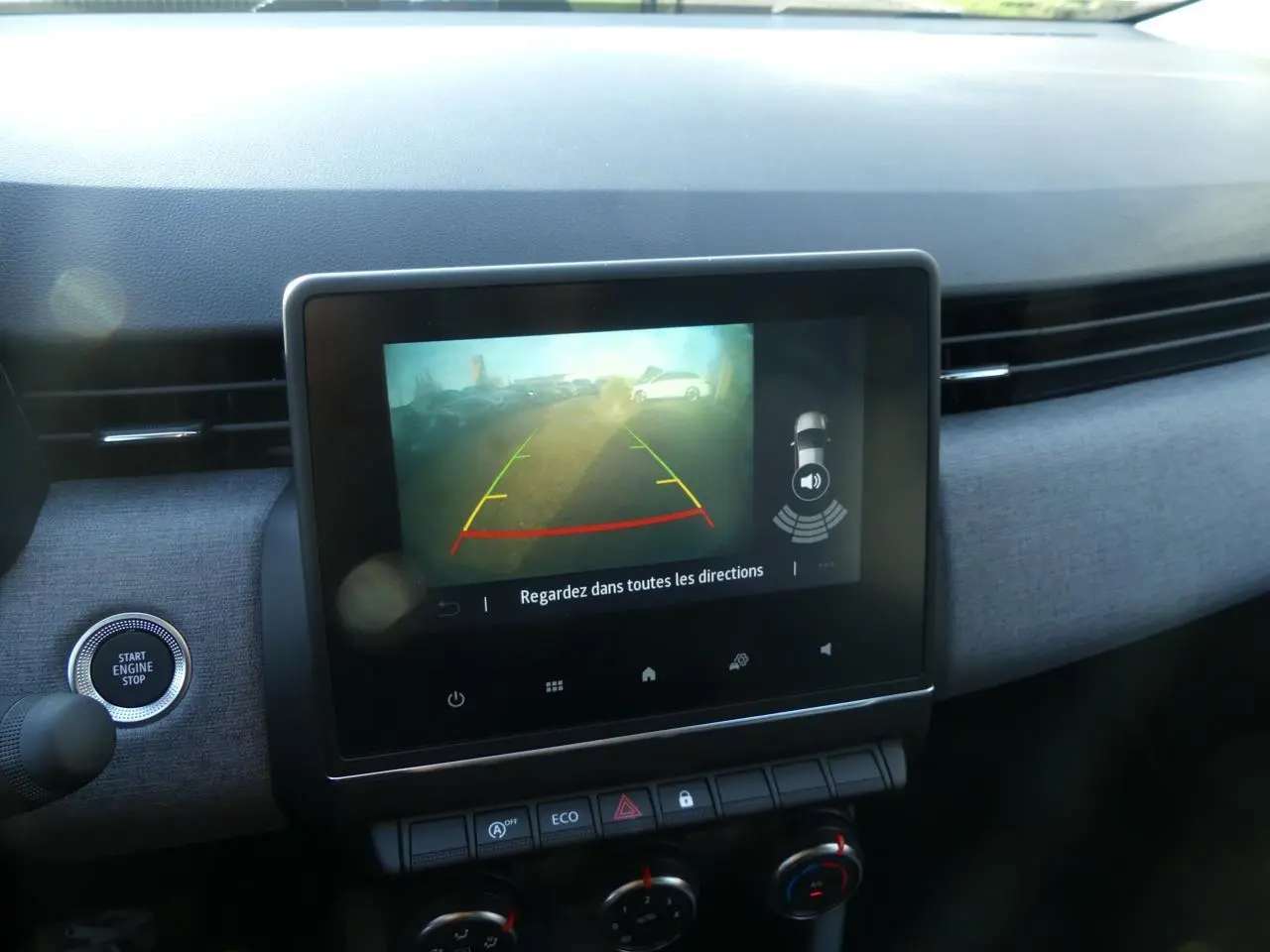 Écran tactile central affichant la caméra de recul dans l'habitacle de la Renault Clio gris schiste, vue de face.