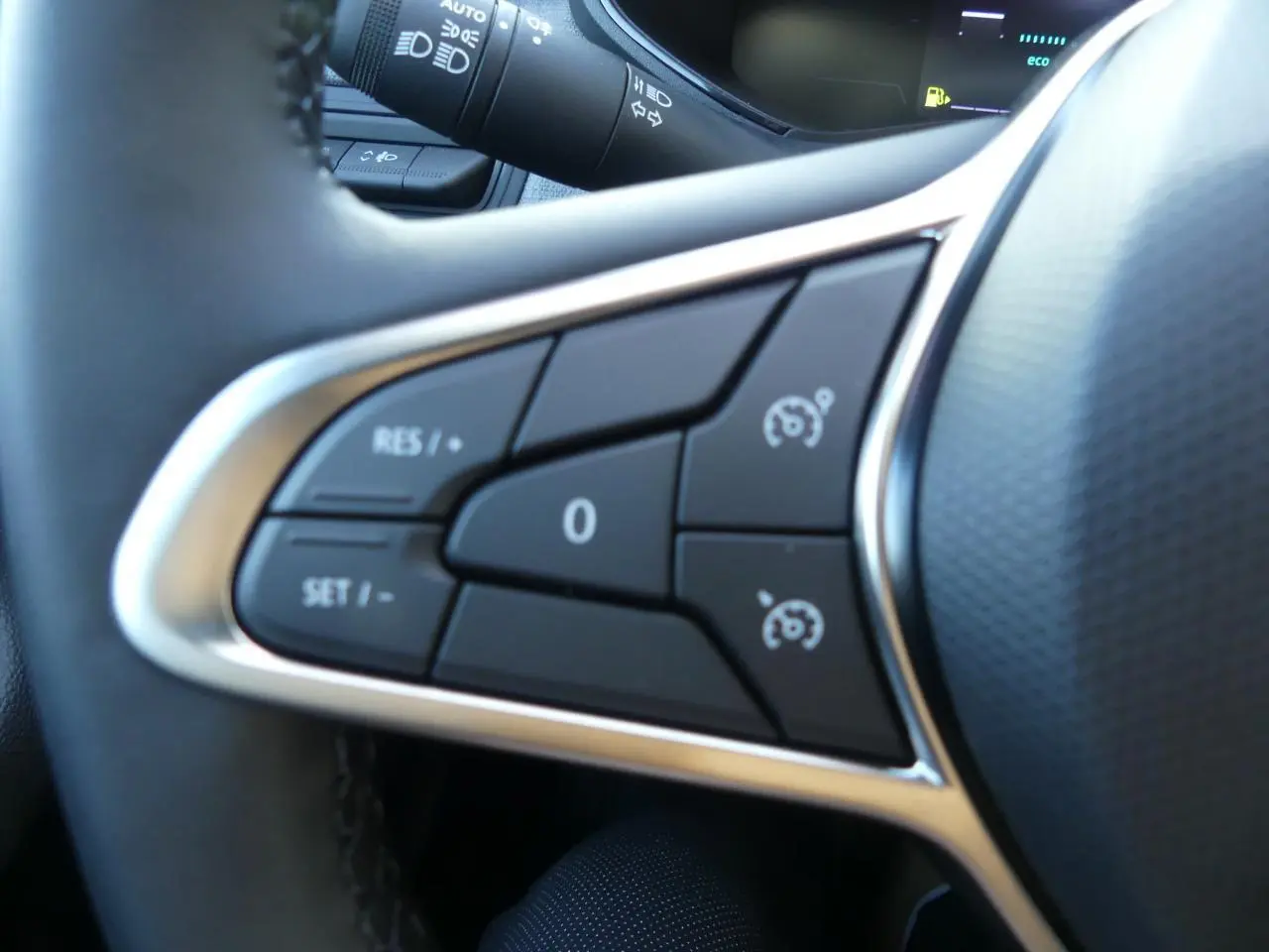 Gros plan sur les commandes de régulateur de vitesse du volant noir de la Renault Clio 1.5 Blue dCi gris schiste.