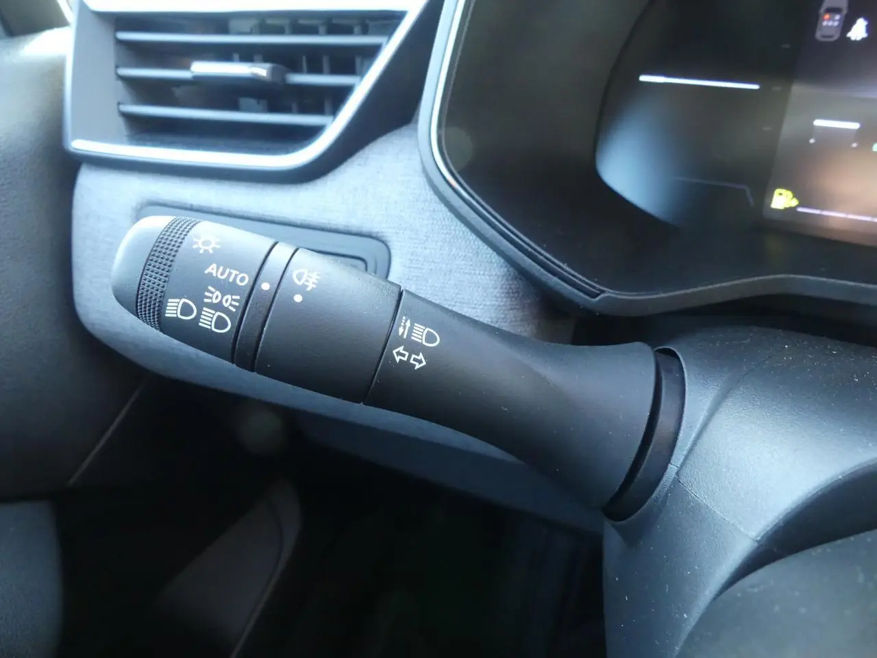 Gros plan sur la manette de commande des feux et clignotants dans l'habitacle gris de la Renault Clio 2025.