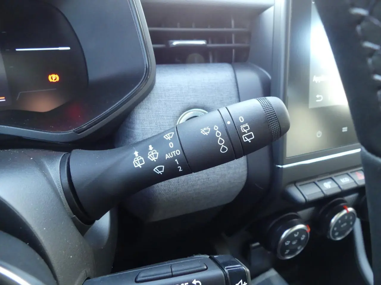 Gros plan sur la commande d'essuie-glace à gauche du volant dans l'habitacle gris et noir de la Renault Clio 2025.