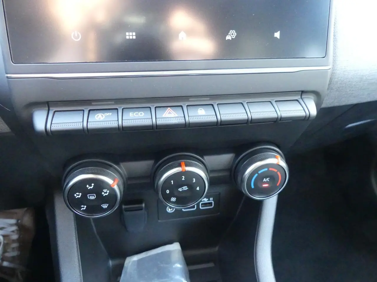 Gros plan sur la console centrale de la Renault Clio 1.5 Blue dCi 2025 avec commandes de climatisation et boutons fonctionnels.