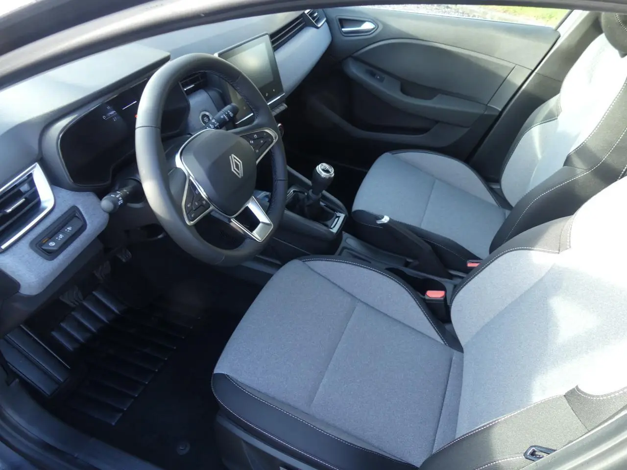 Vue intérieure côté conducteur de la Renault Clio 1.5 Blue dCi 2025 avec sièges tissu gris et volant multifonction.