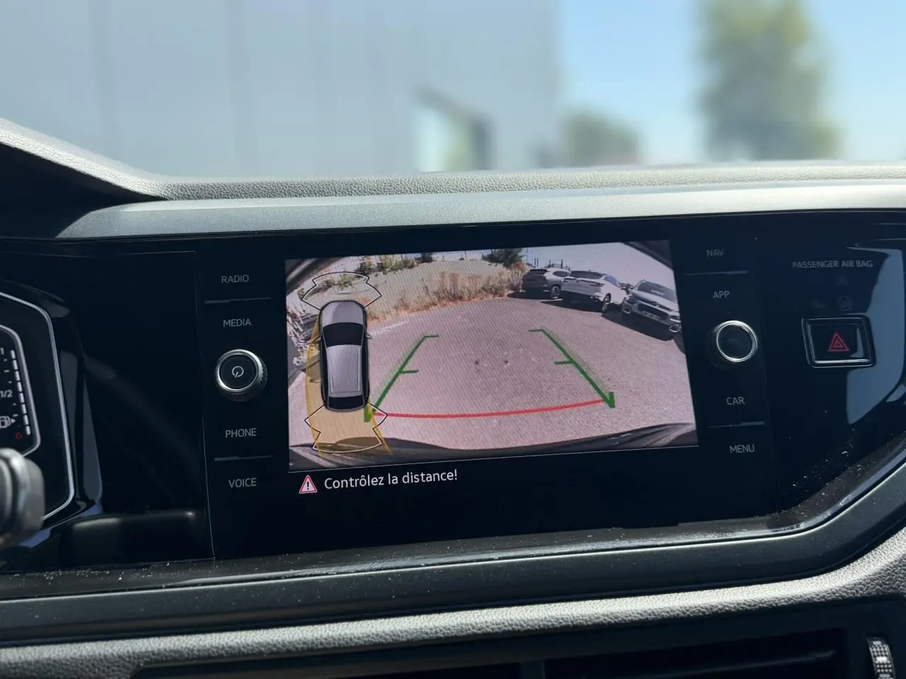Vue intérieure du tableau de bord du Volkswagen Taigo 2025 noir, écran affichant la caméra de recul avec aides au stationnement.