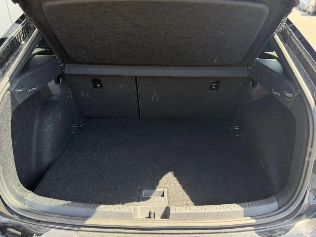 Coffre ouvert noir du Volkswagen Taigo TSI 116 DSG R-Line 2025, montrant l'espace de chargement vide et doublure noire.