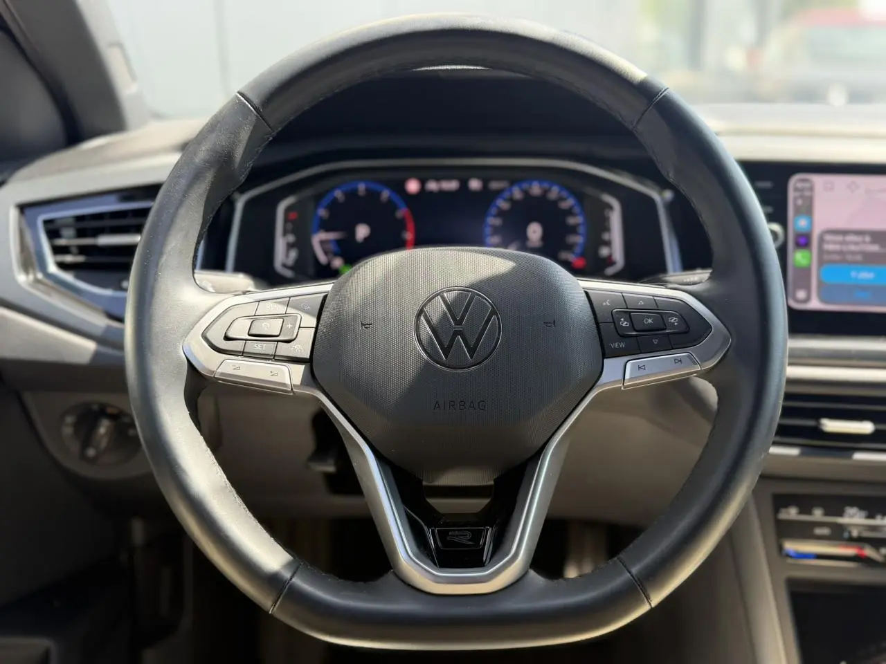 Vue rapprochée du volant cuir multifonctions noir du Volkswagen Taigo TSI 116 DSG R-Line avec tableau de bord digital.