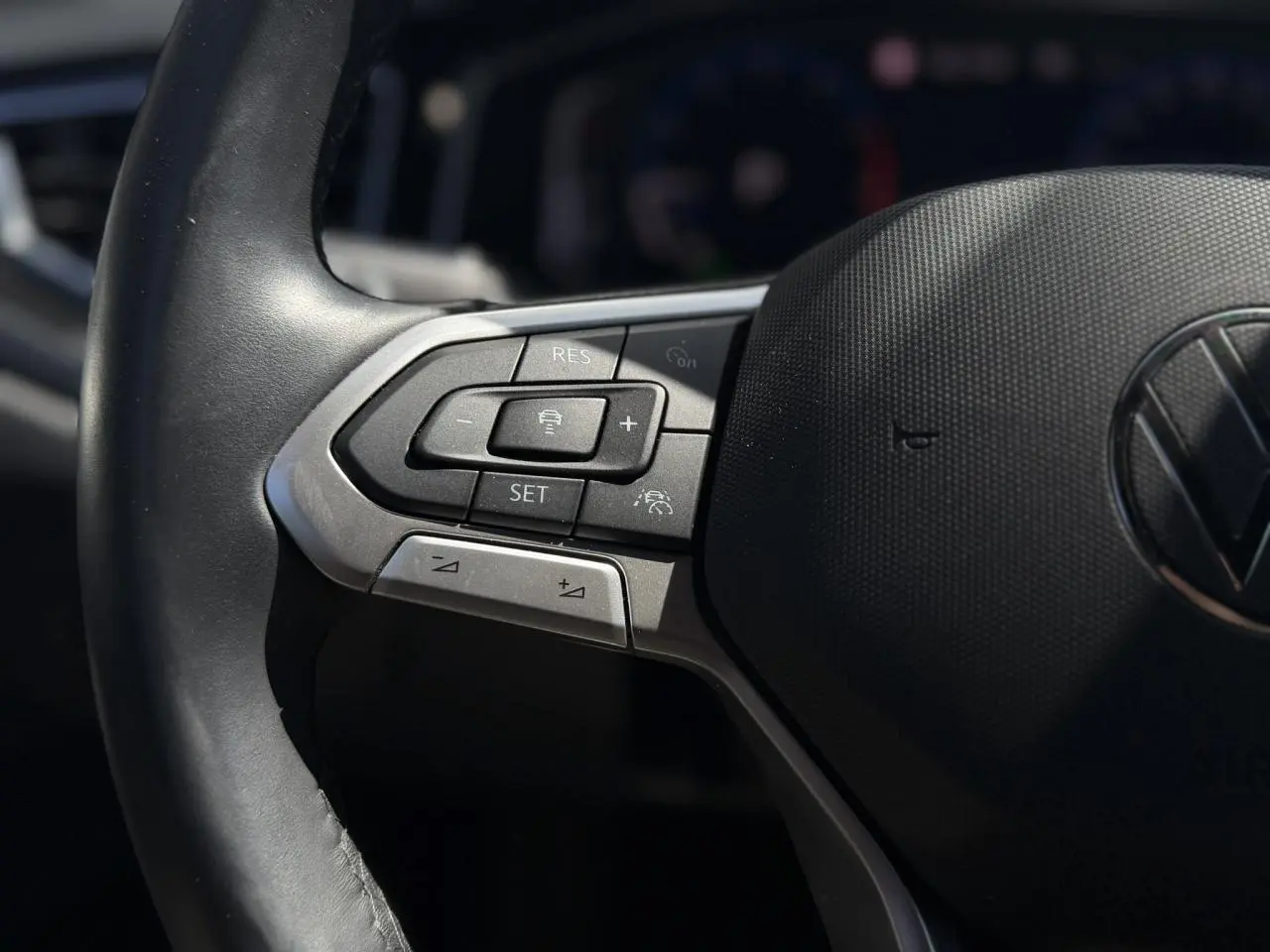Gros plan sur les commandes gauche du volant cuir noir du Volkswagen Taigo TSI 116 DSG R-Line 2025.
