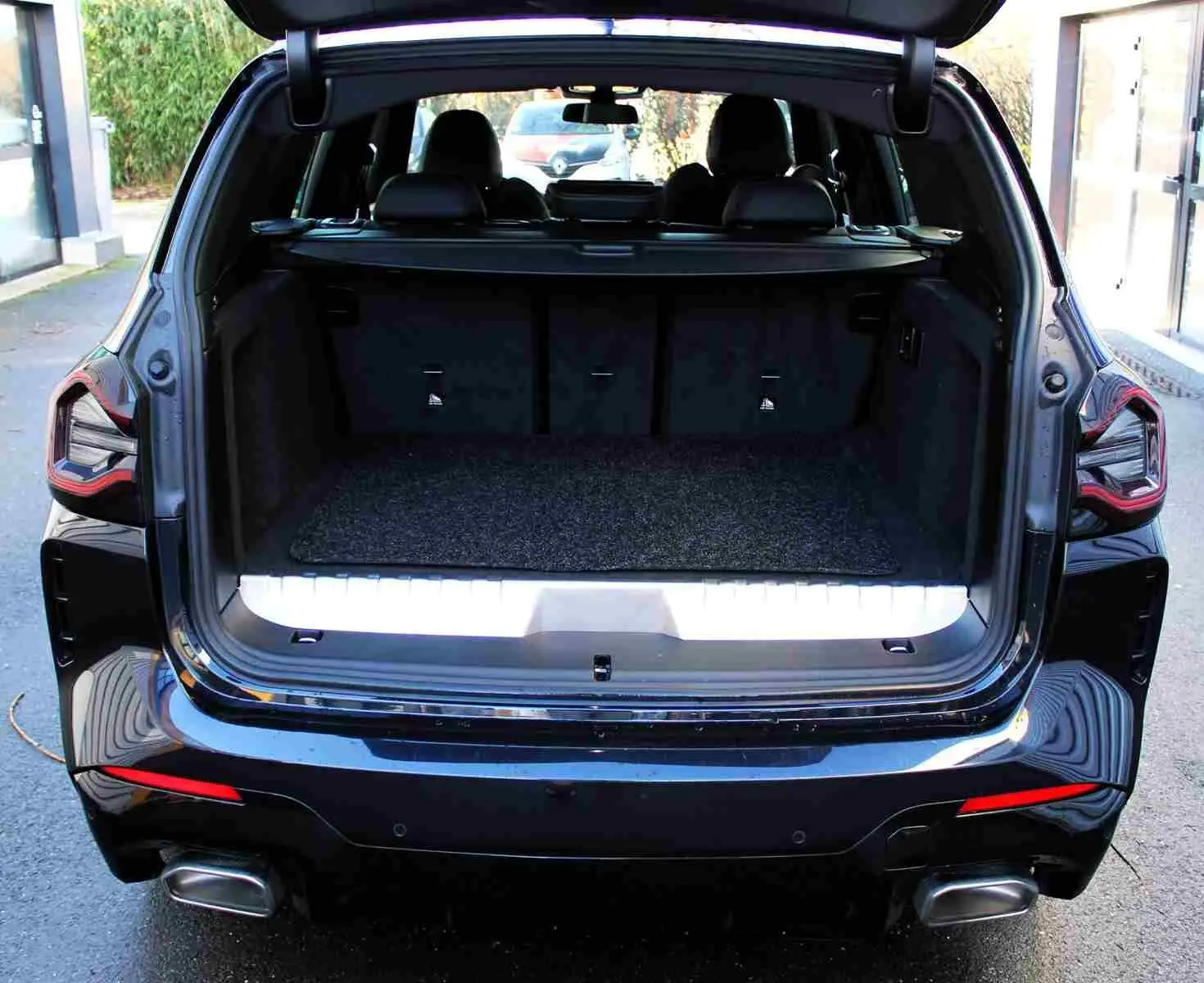 Coffre ouvert vu de l'arrière d'un BMW X3 xDrive bleu métal 2023, avec banquette arrière et feux LED visibles.