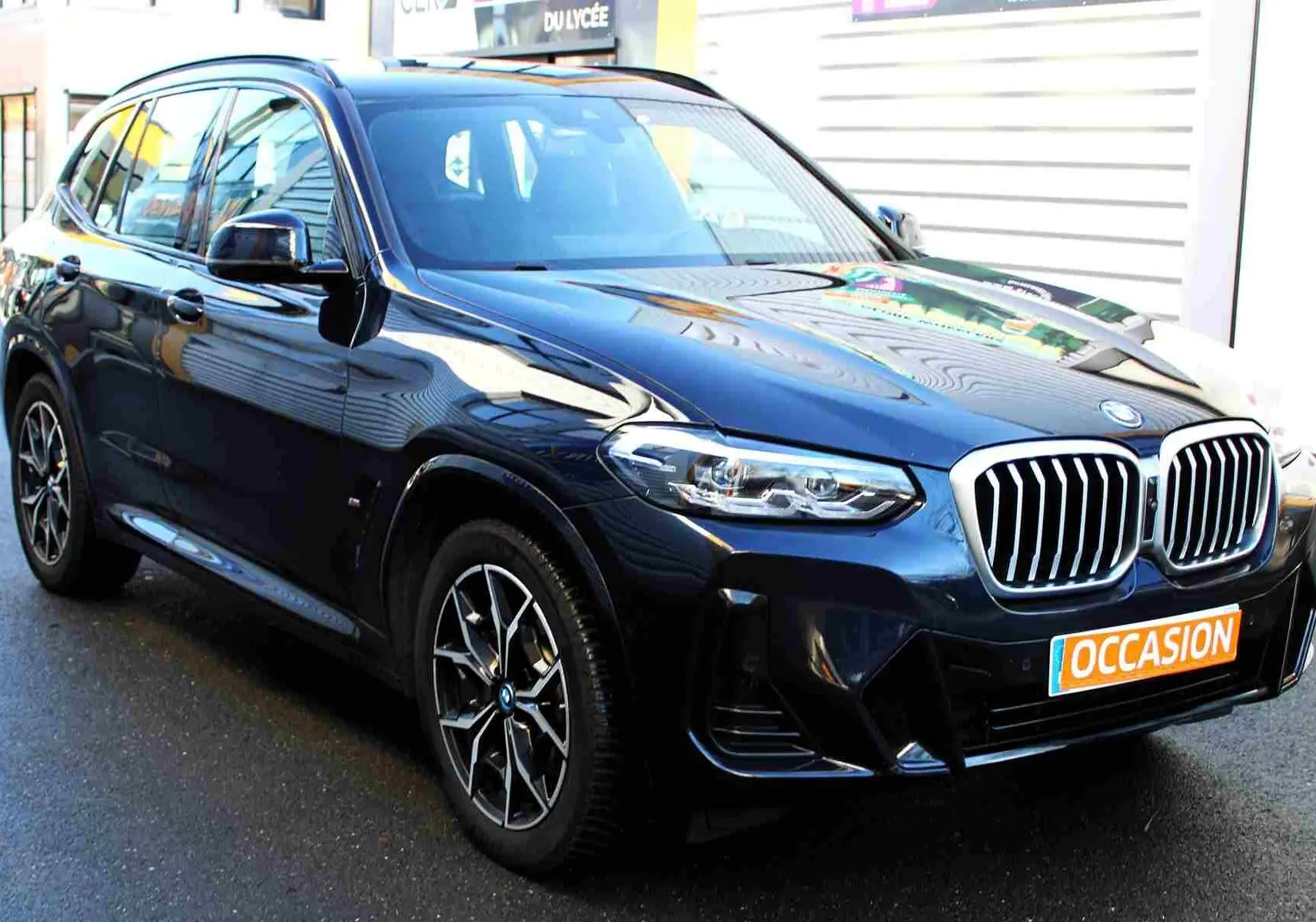 BMW X3 xDrive 30e bleu métal en 3/4 avant droit, avec calandre double haricot et jantes M Sport visibles.