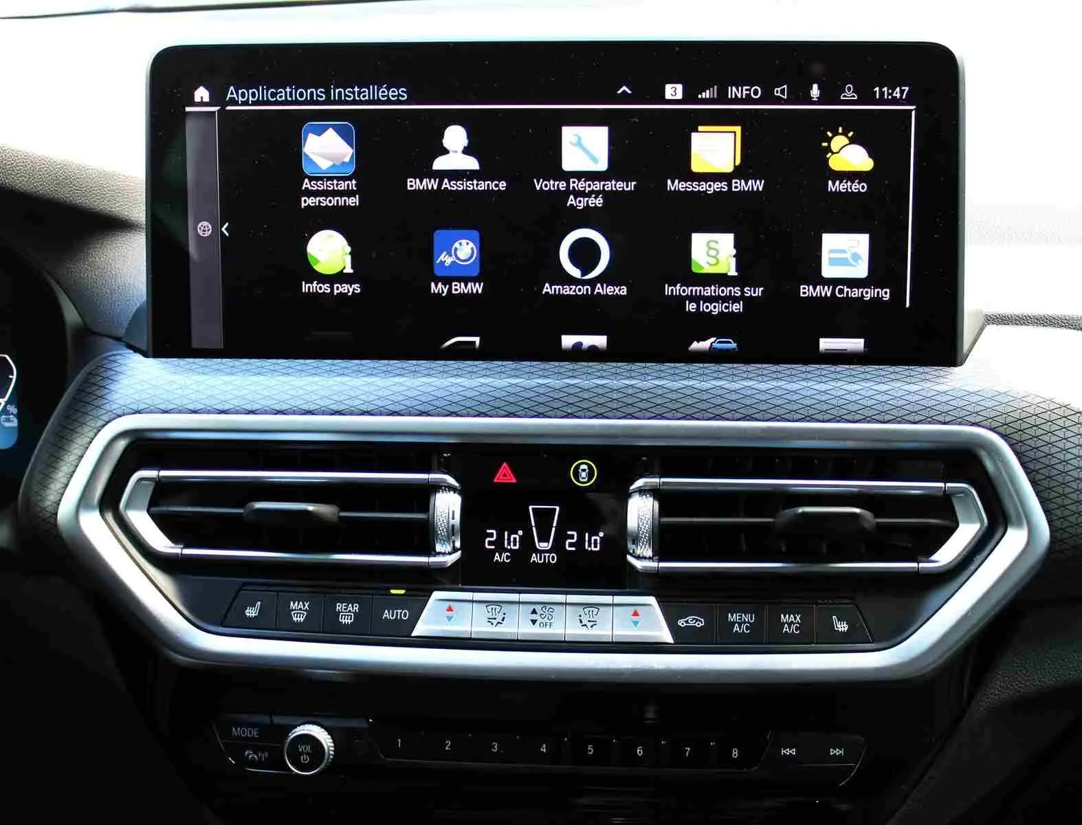 Vue rapprochée de la console centrale du BMW X3 xDrive 30e 2023, écran tactile et commandes climatisation visibles.