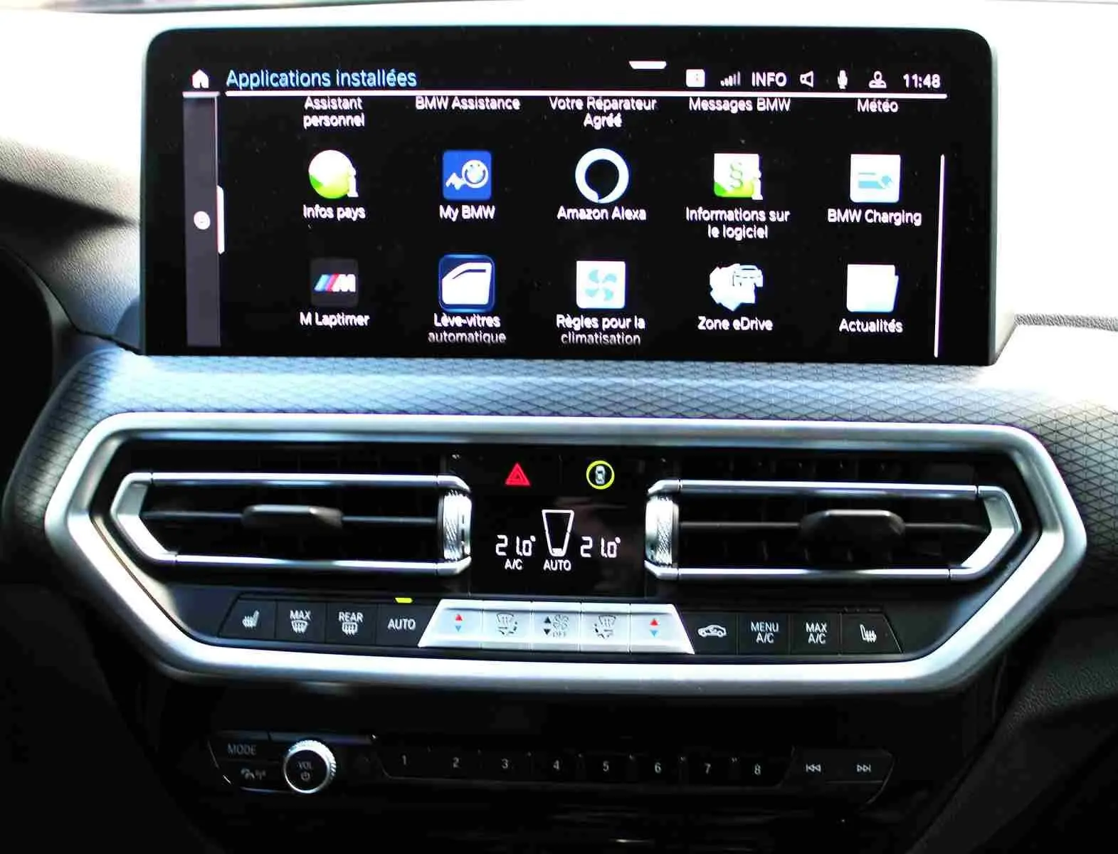 Tableau de bord du BMW X3 xDrive 30e 2023 avec écran tactile affichant les applications et commandes de climatisation.