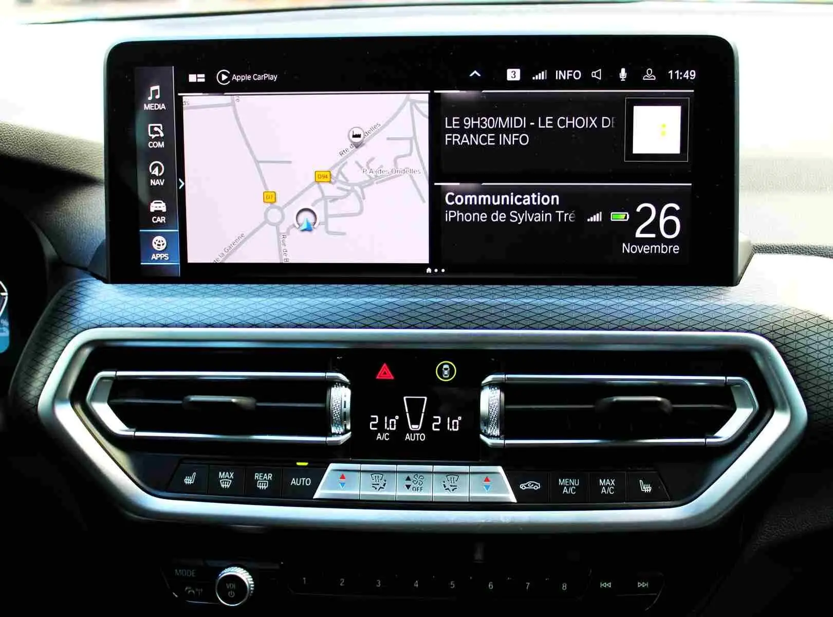 Tableau de bord BMW X3 xDrive 30e 2023 avec écran tactile et commandes climatisation en vue frontale rapprochée.