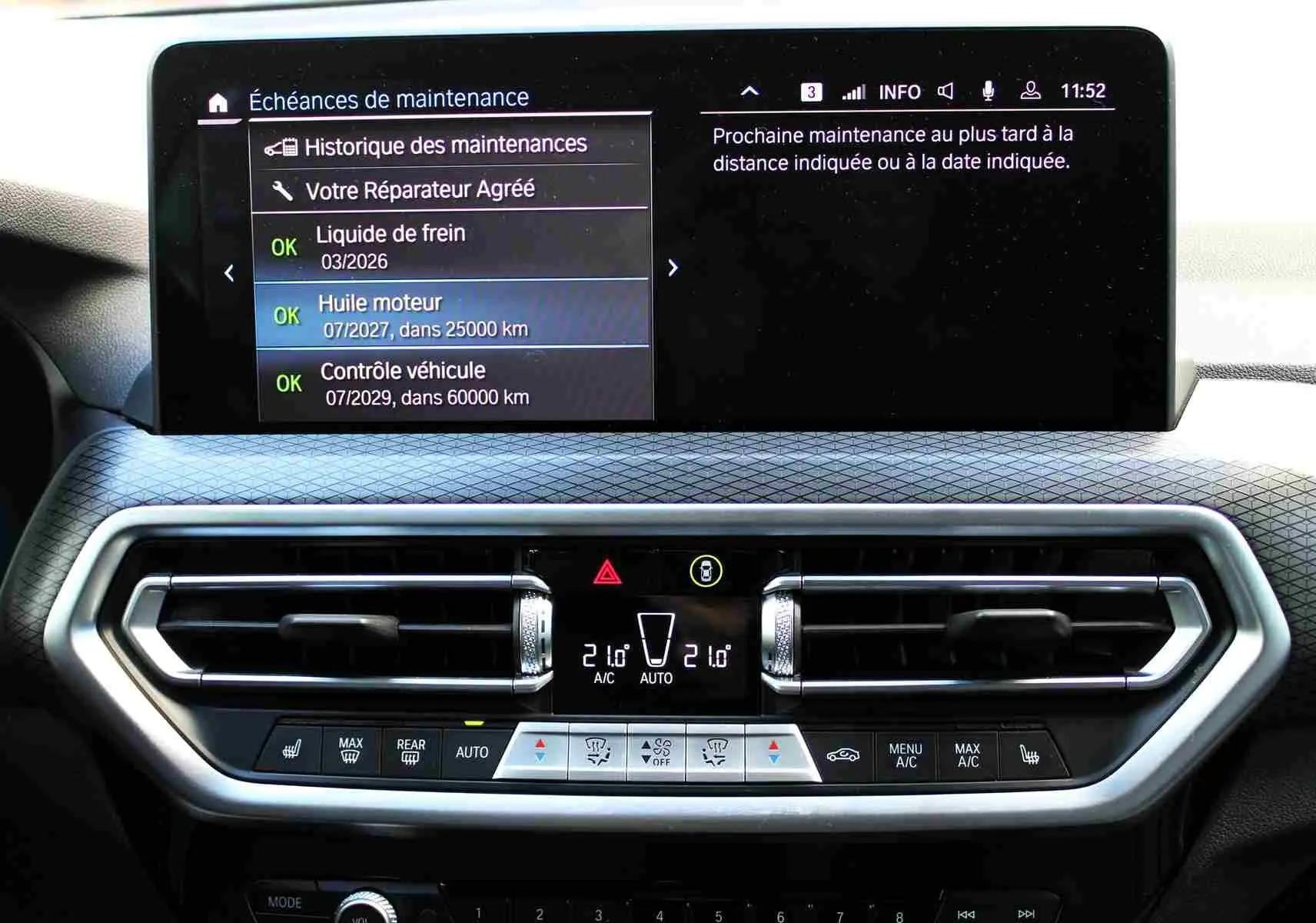 Tableau de bord du BMW X3 xDrive 30e 2023 avec écran central affichant l'entretien et commandes de climatisation.