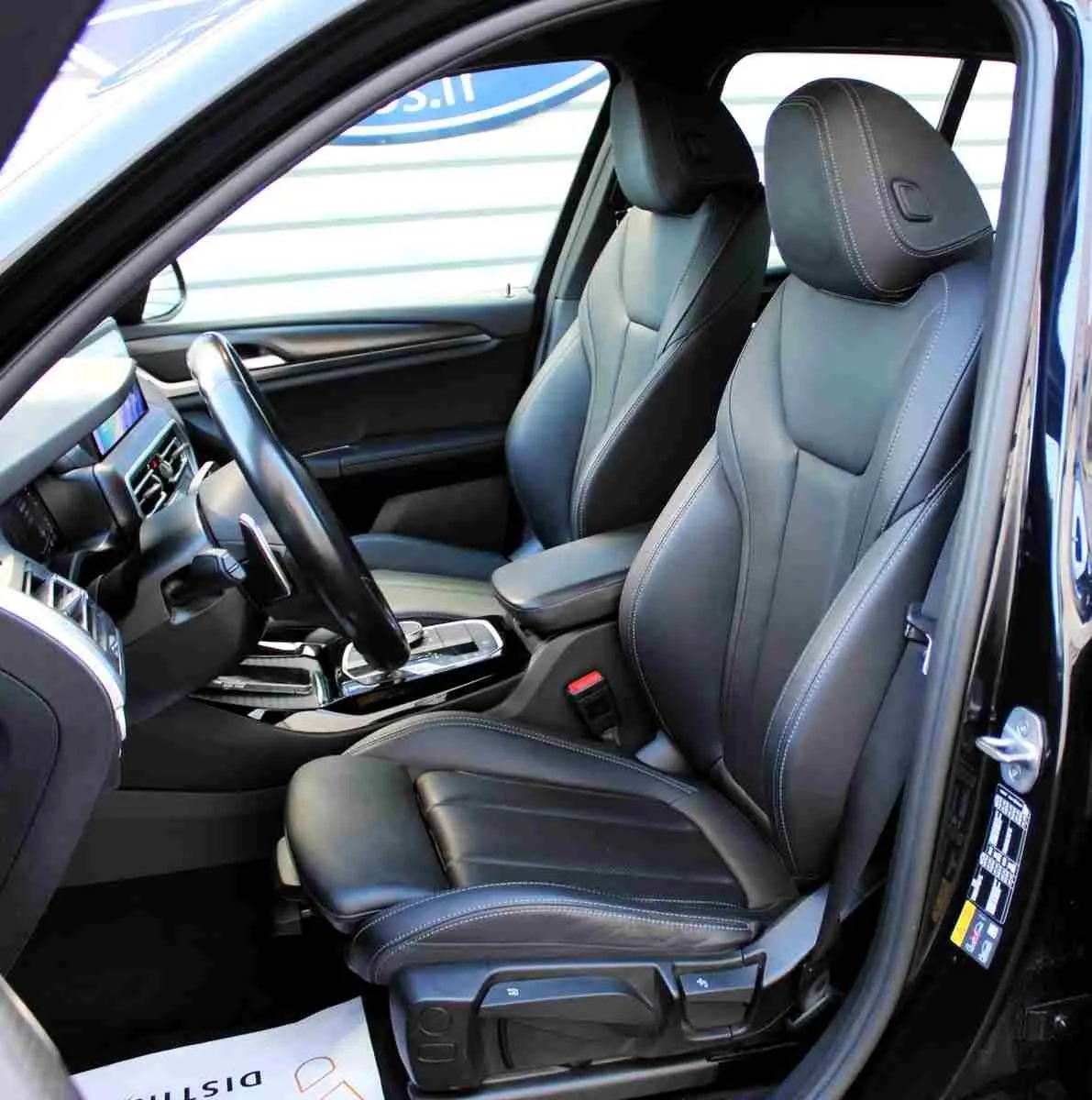 Vue intérieure côté conducteur du BMW X3 xDrive 30e 2023, sièges sport en cuir noir avec surpiqûres contrastées.