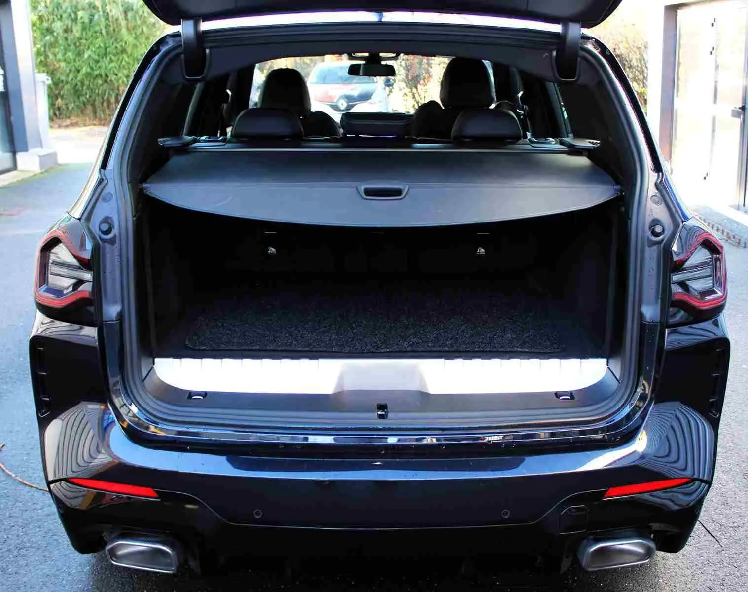 Vue arrière d'un BMW X3 xDrive 30e 2023 bleu métal avec coffre ouvert et banquette arrière visible.