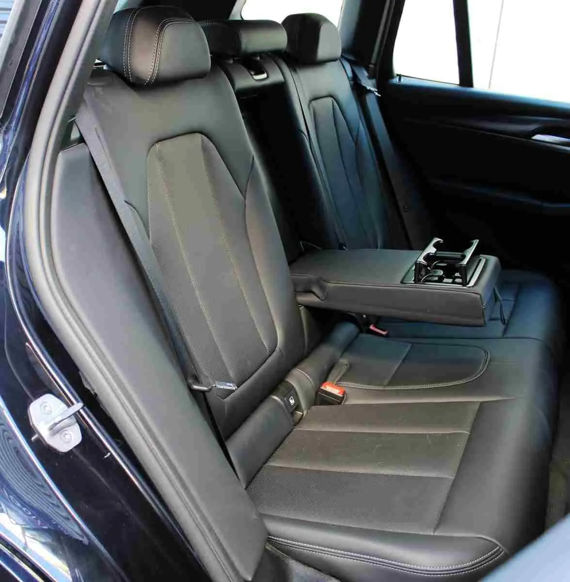 Vue intérieure côté gauche des sièges arrière en cuir noir avec accoudoir central déplié du BMW X3 xDrive 30e 2023.