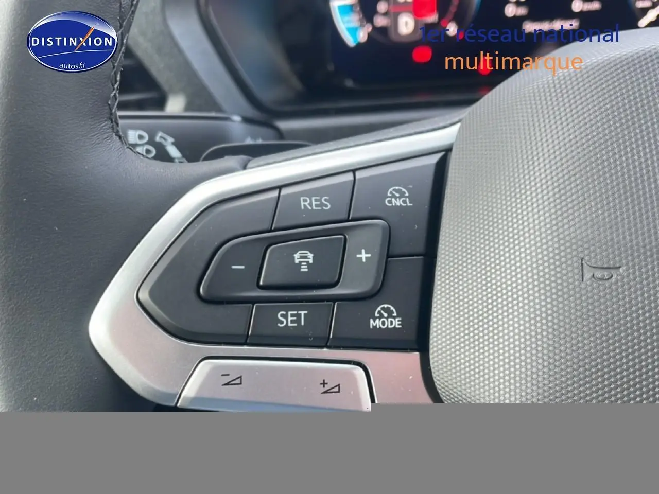 Gros plan sur les commandes au volant cuir multifonction du Volkswagen Caddy gris argent, mettant en valeur les boutons d'assistance à la conduite.