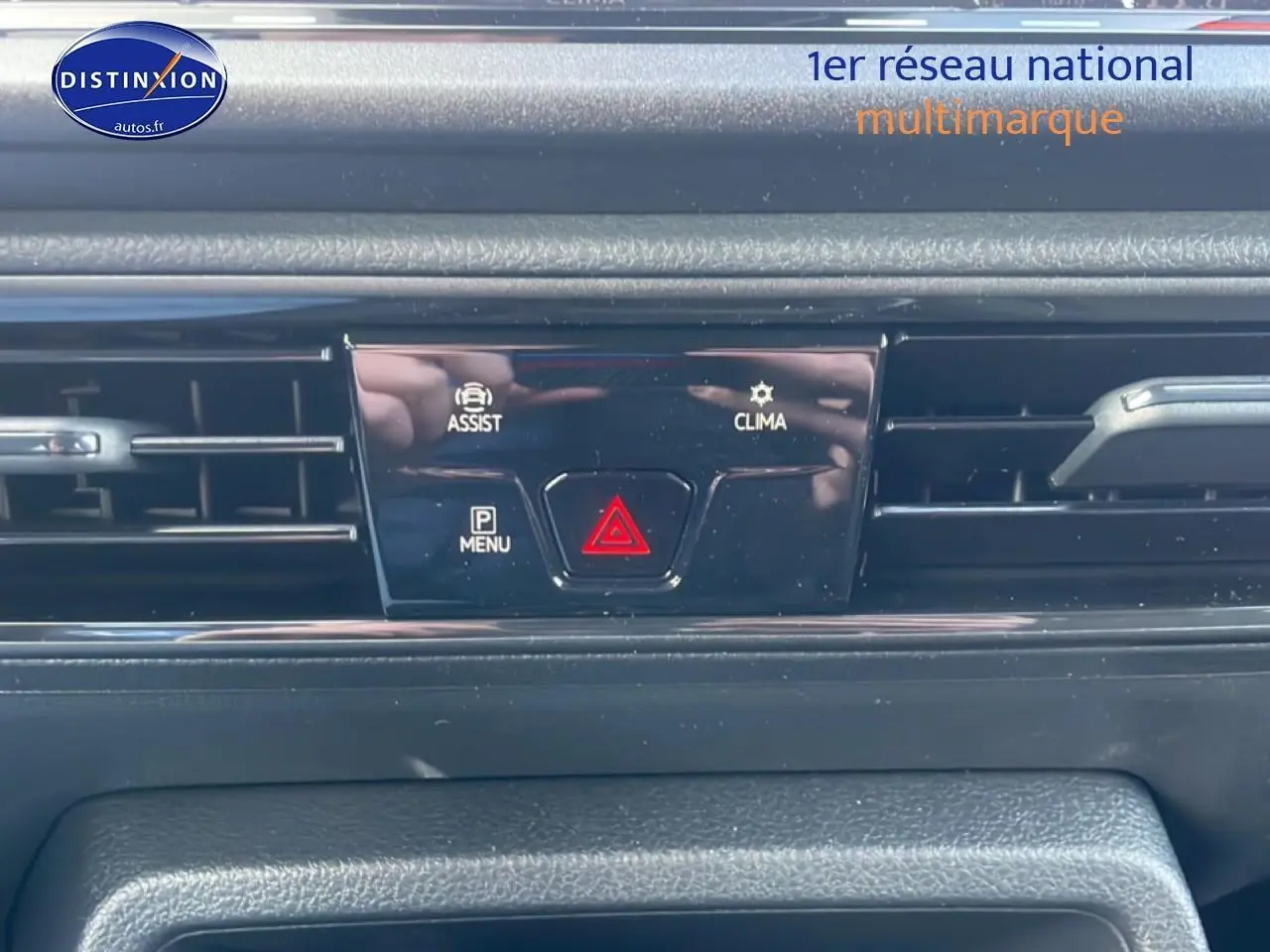 Gros plan sur la console centrale noire du Volkswagen Caddy gris argent, avec boutons d'assistance et climatisation visibles.