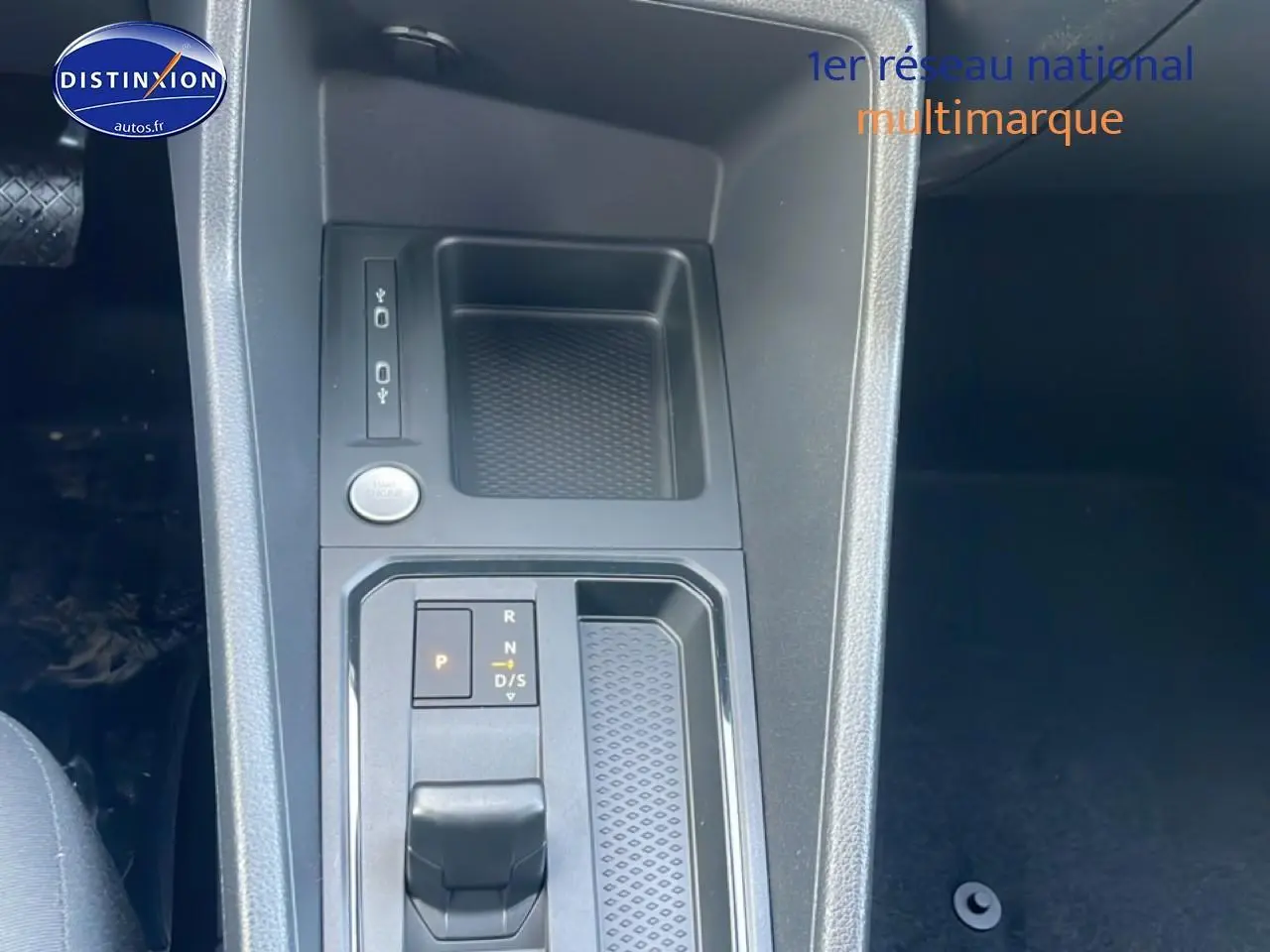 Gros plan sur la console centrale du Volkswagen Caddy gris argent, mettant en valeur le levier de vitesse automatique et le bouton start/stop.