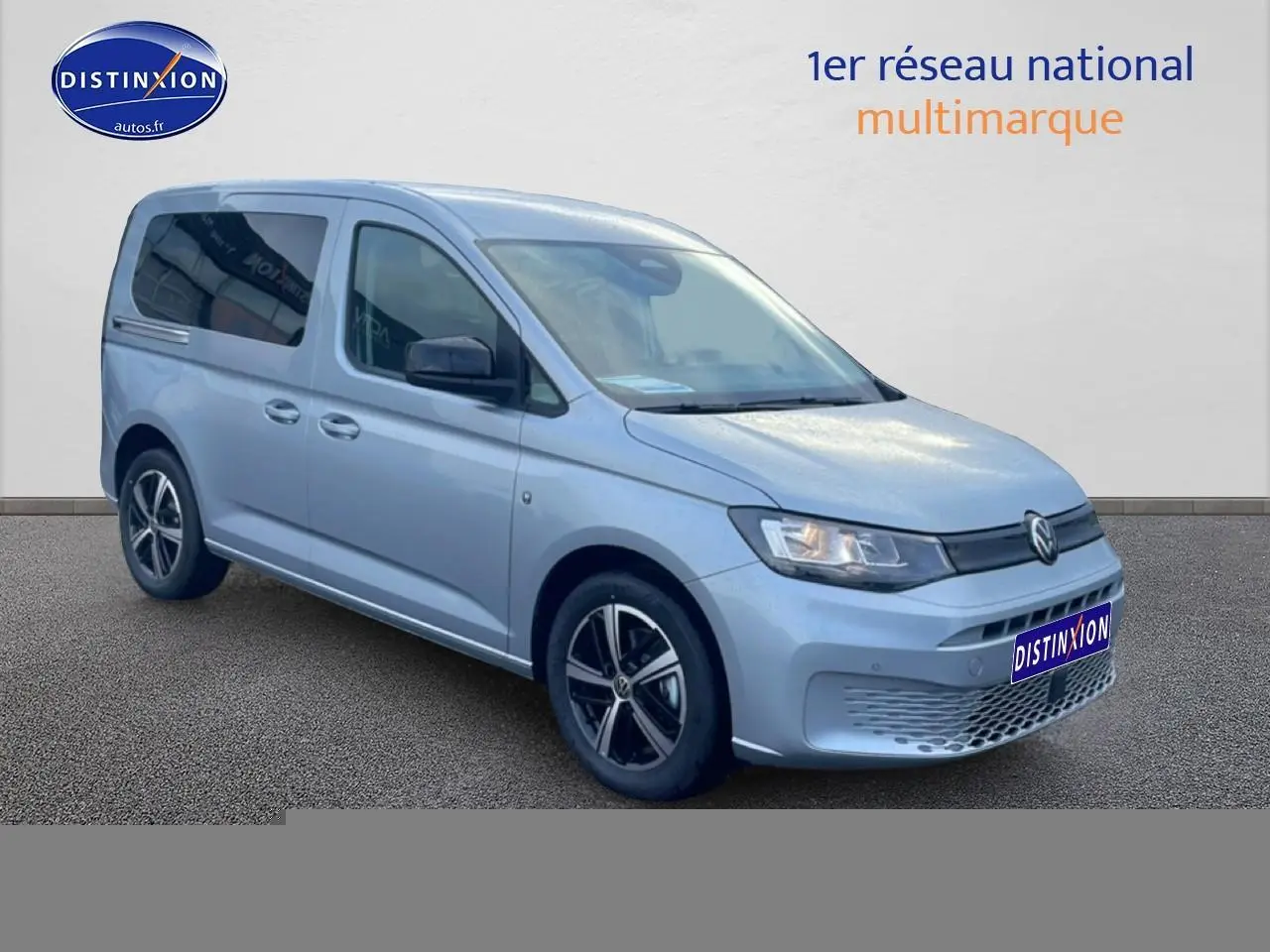 Vue 3/4 avant droit d'un Volkswagen Caddy gris argent 2025 avec jantes alliage et vitres teintées.