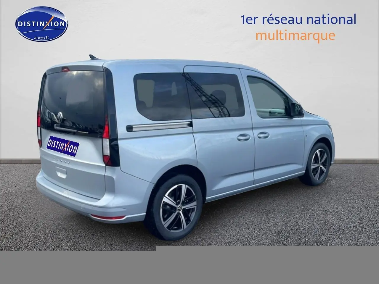 Vue 3/4 arrière droite d'un Volkswagen Caddy gris argent 2025 avec vitres arrière teintées et jantes alliage.