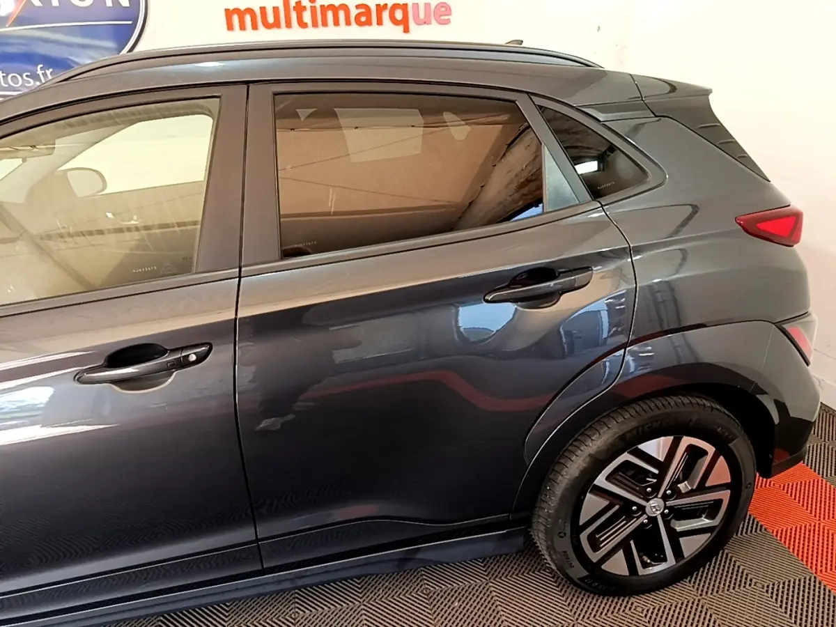 Vue latérale droite d'une Hyundai Kona électrique 2021 gris foncé avec jantes spécifiques et vitres teintées.