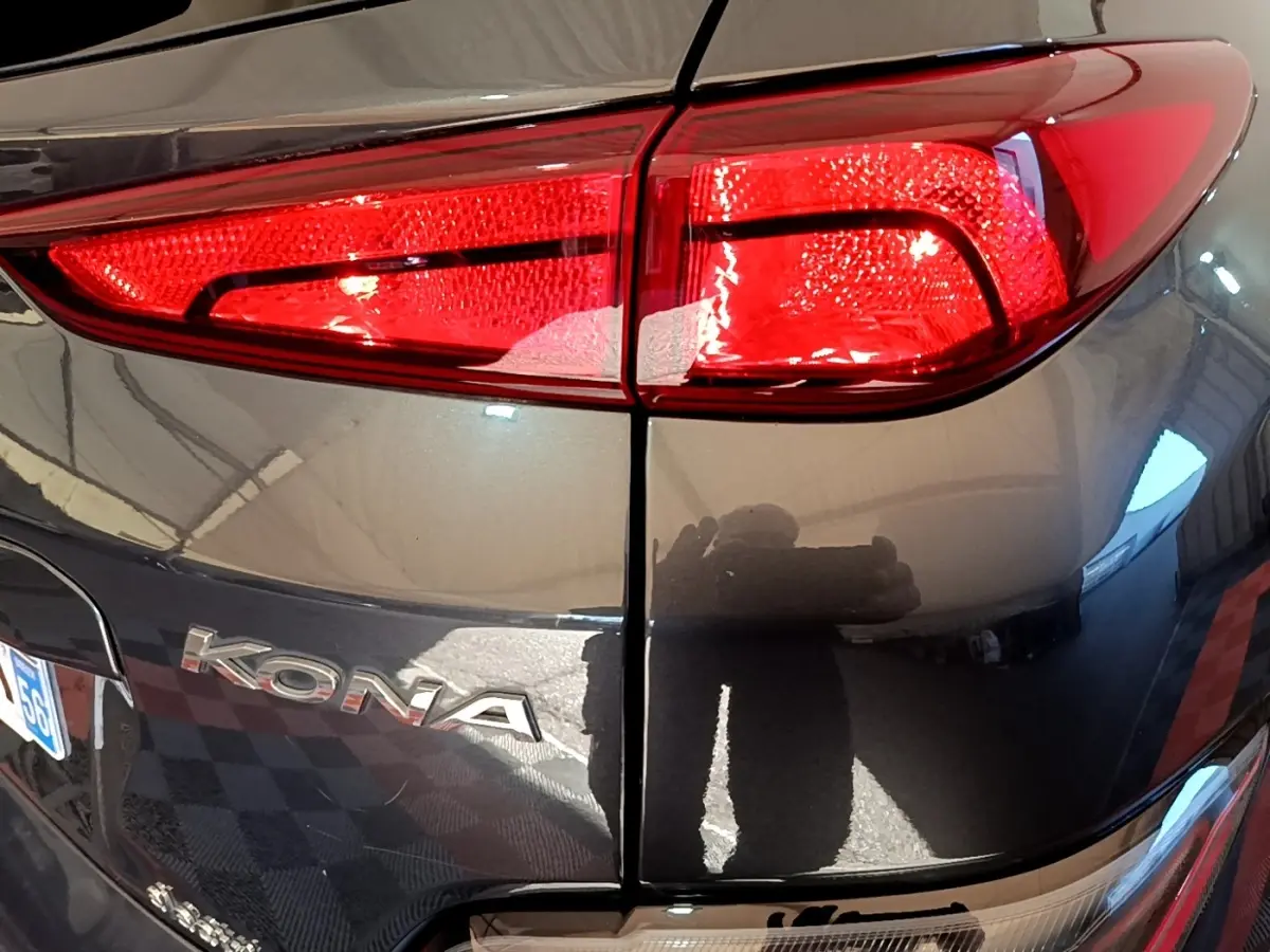 Gros plan sur le feu arrière droit rouge et la carrosserie gris foncé d’une Hyundai KONA électrique 2021.