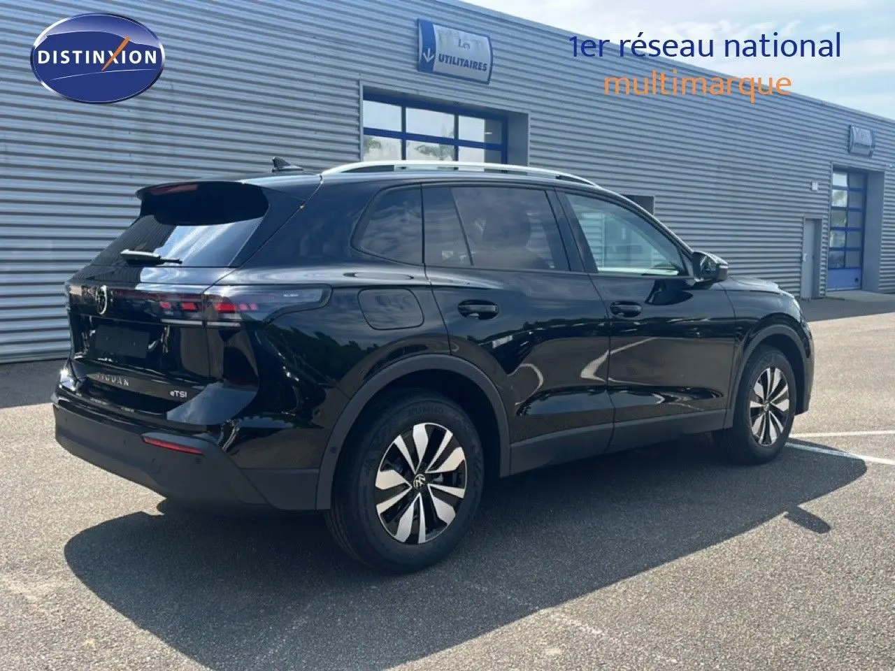 Vue 3/4 arrière droite d’un Volkswagen Tiguan noir Grenadilla métallisé avec jantes bicolores et toit argenté.