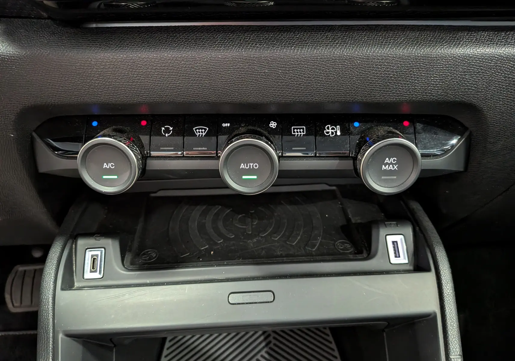 Vue rapprochée de la console centrale de la Citroën C4 Hybride 2025, montrant les commandes de climatisation et ports USB.