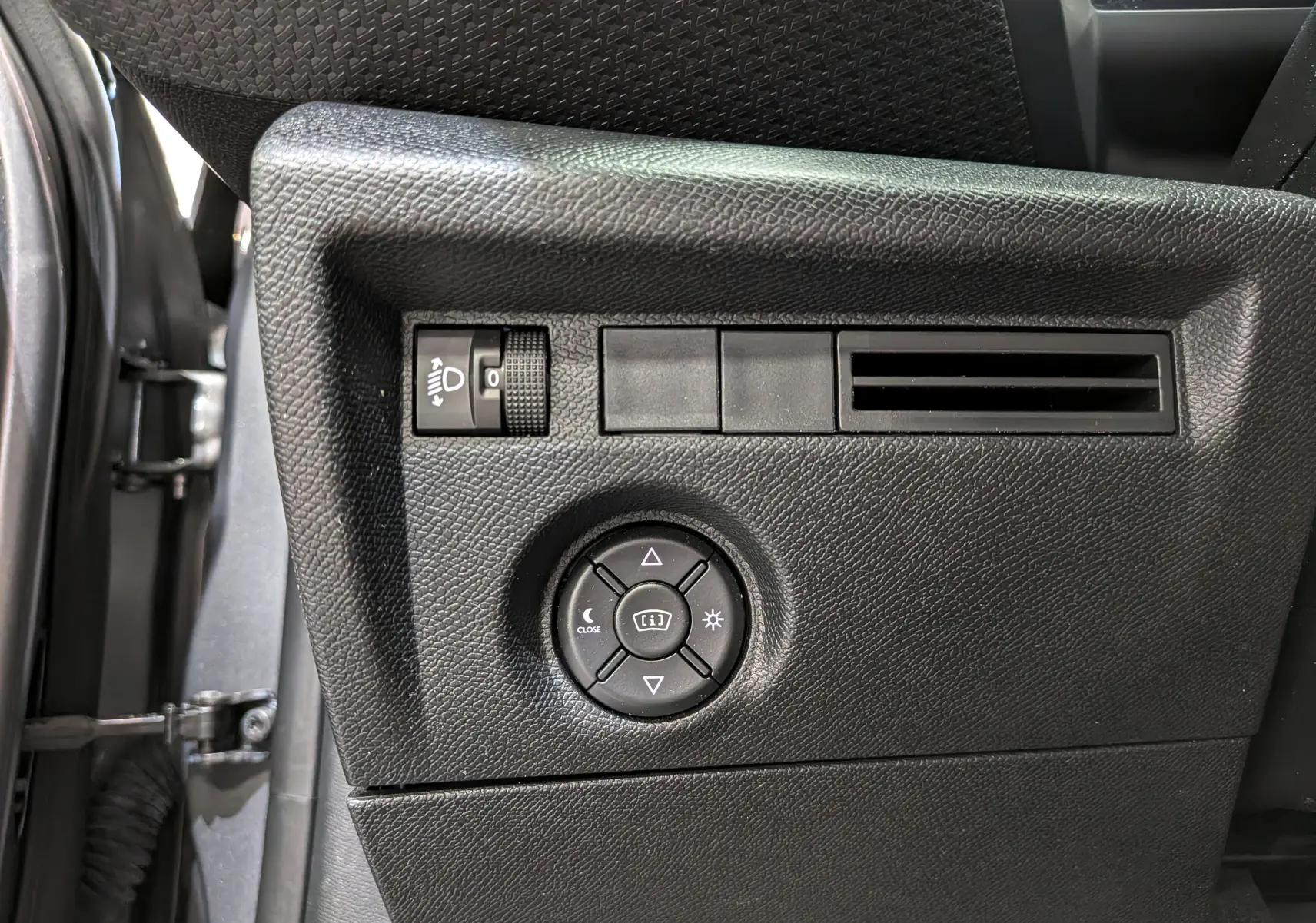 Vue rapprochée du panneau de commandes côté gauche intérieur d'une Citroën C4 gris Mercury, avec réglage des phares et ventilation.