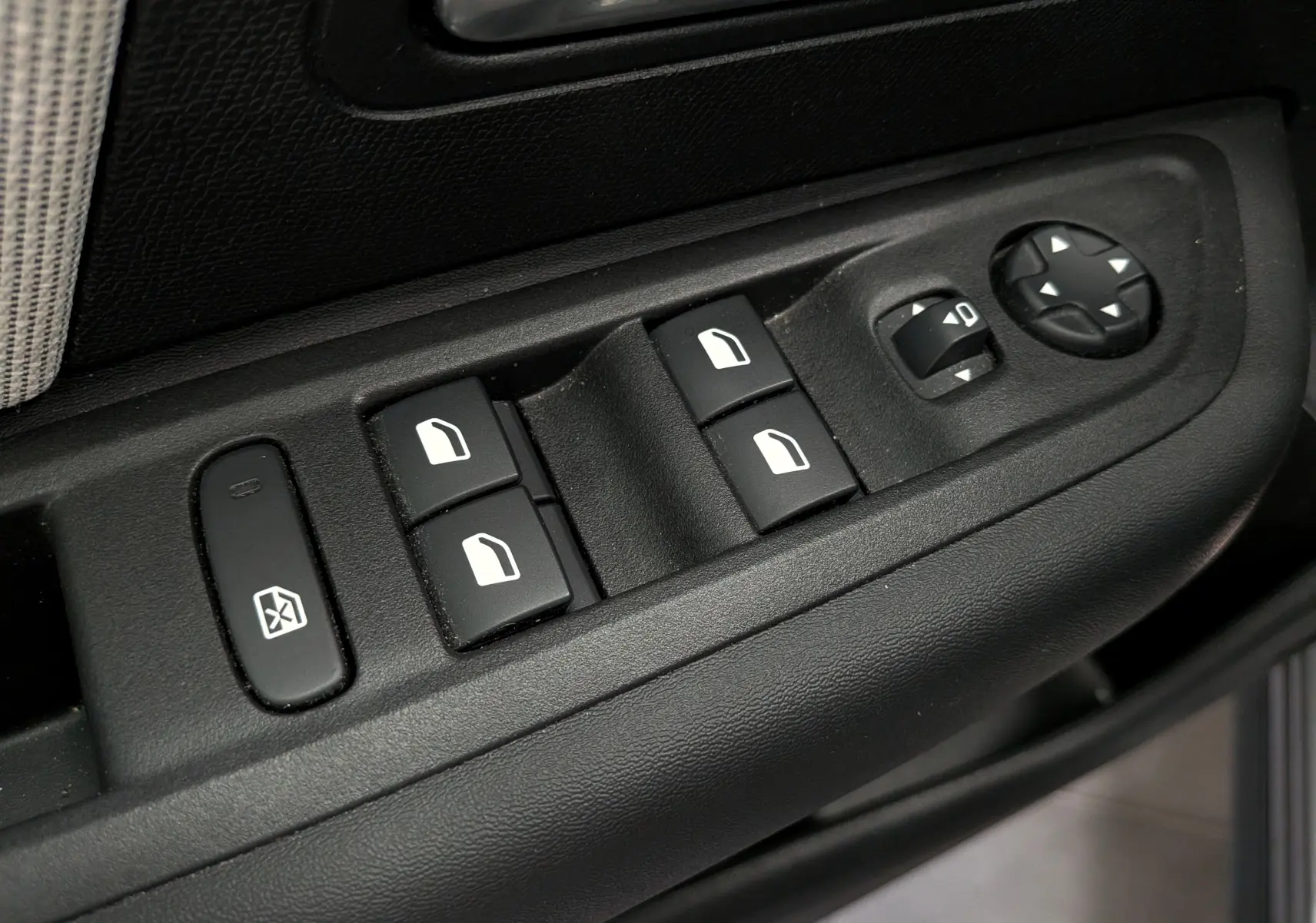 Gros plan sur les commandes de lève-vitres et réglages des rétroviseurs côté conducteur d'une Citroën C4 Hybride gris Mercury.