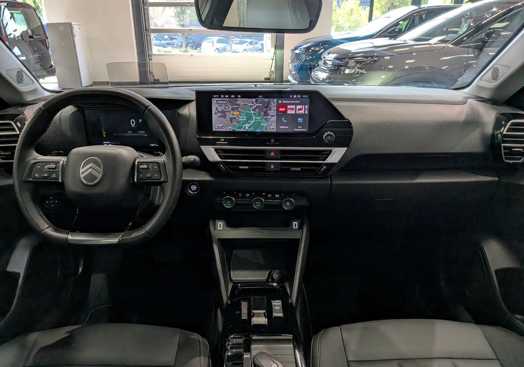Vue intérieure du tableau de bord de la Citroën C4 Hybride 2025 avec écran tactile central et volant multifonction noir.