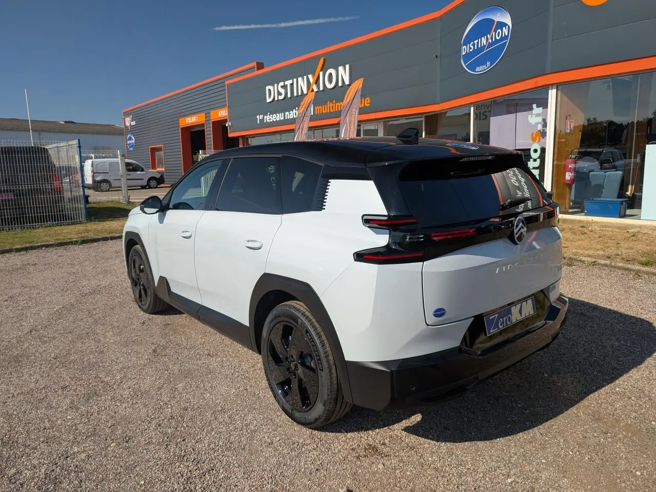Vue 3/4 arrière droite du Citroën C5 Aircross blanc avec toit noir et jantes alliage noires sur parking.
