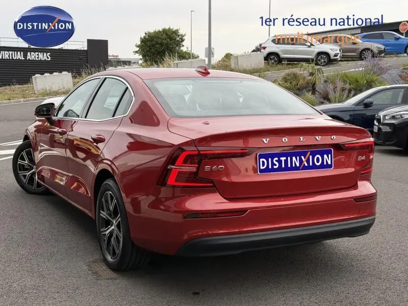 Vue 3/4 arrière droite d'une Volvo S60 2024 Rouge Fusion Métallisé avec feux arrière LED et logo distinctif.