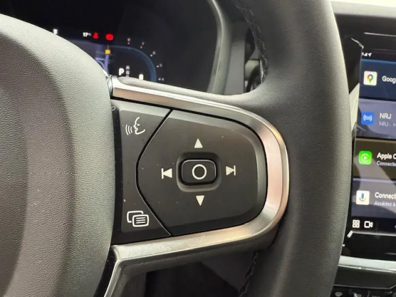 Gros plan sur les commandes au volant d'une Volvo S60 2024, avec écran tactile et interface connectée visible.