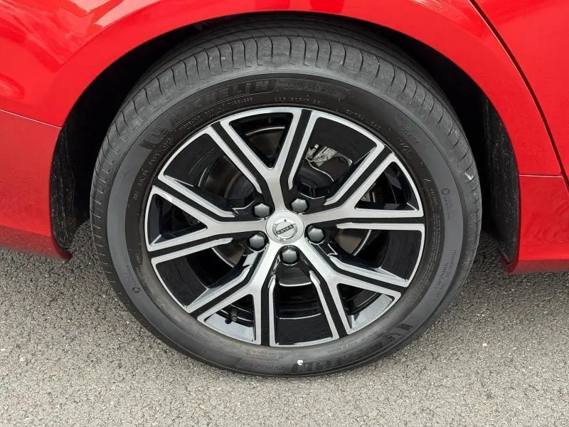 Gros plan sur la roue avant droite de la Volvo S60 2024 rouge Fusion Métallisé avec jante alliage noir et argent.