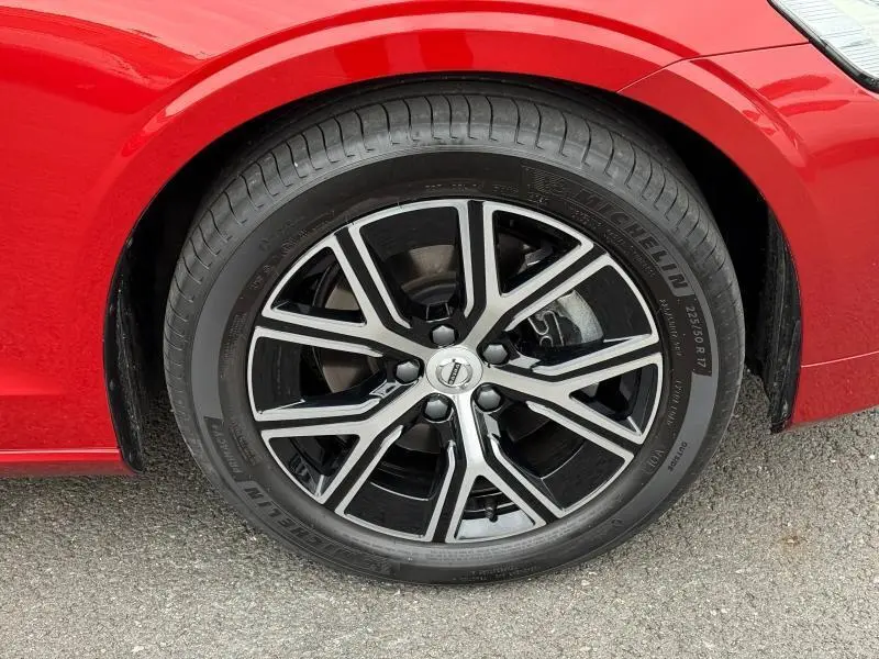 Gros plan sur la roue avant gauche de la Volvo S60 2024 rouge Fusion Métallisé avec jante alliage noire et argentée.