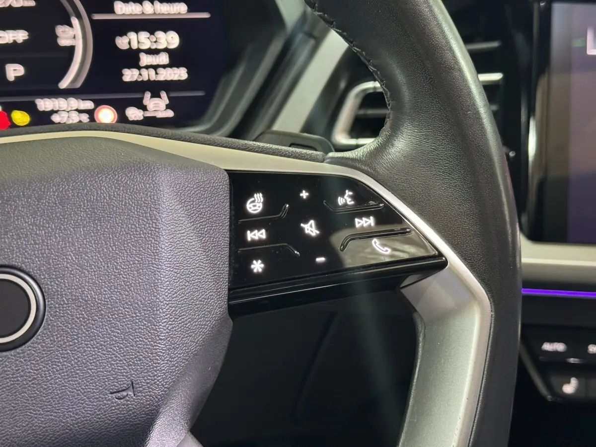Gros plan sur le volant noir de l'Audi Q4 E-TRON 2022 avec commandes tactiles rétroéclairées côté droit.
