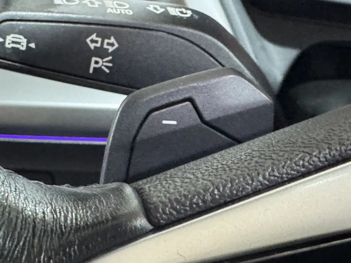 Gros plan sur la palette de commande au volant en cuir noir de l'Audi Q4 E-TRON gris foncé, avec commandes lumineuses.