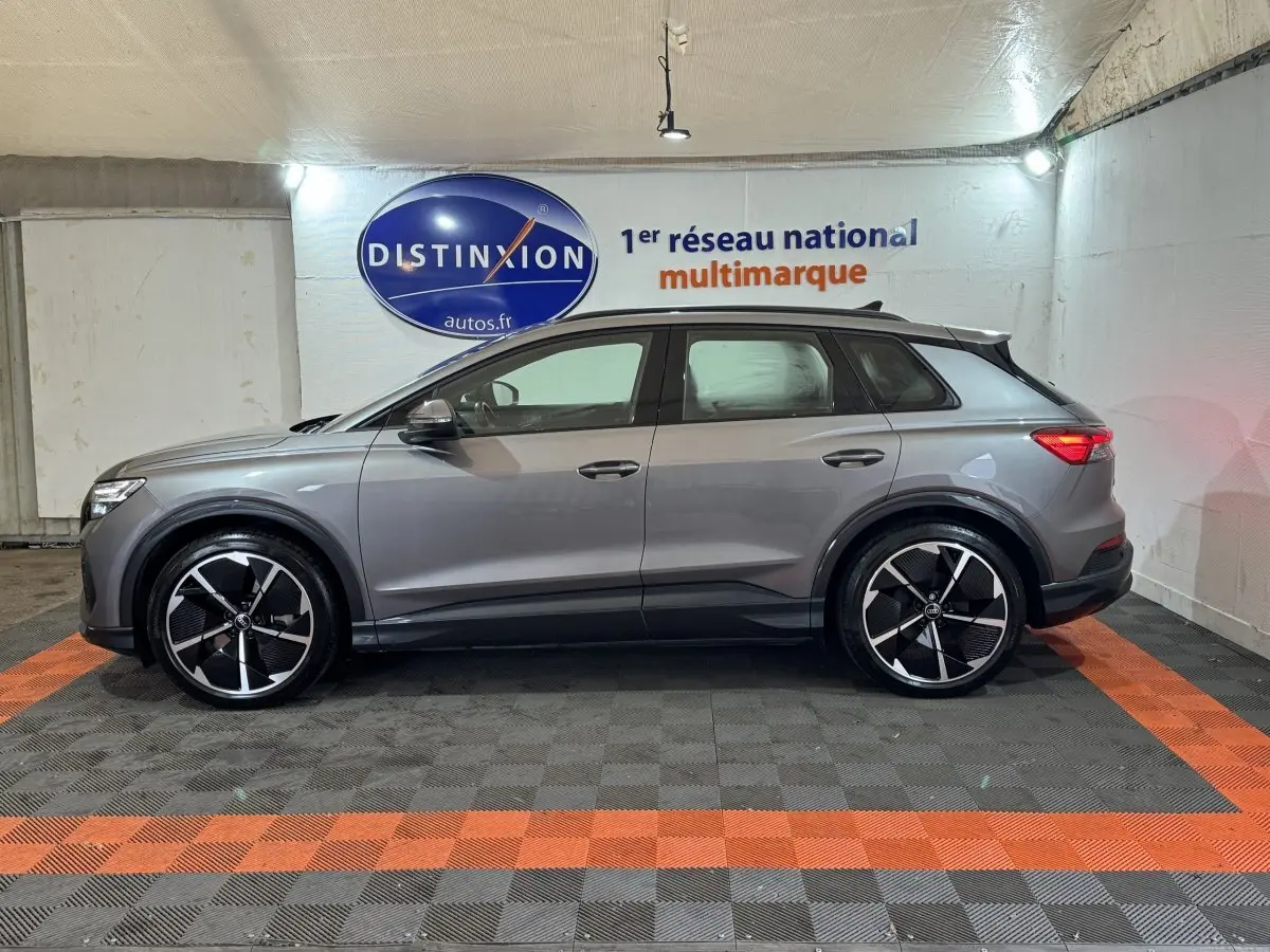 Audi Q4 E-TRON gris foncé vue de profil côté gauche, avec jantes noires et détails noirs sur bas de caisse.