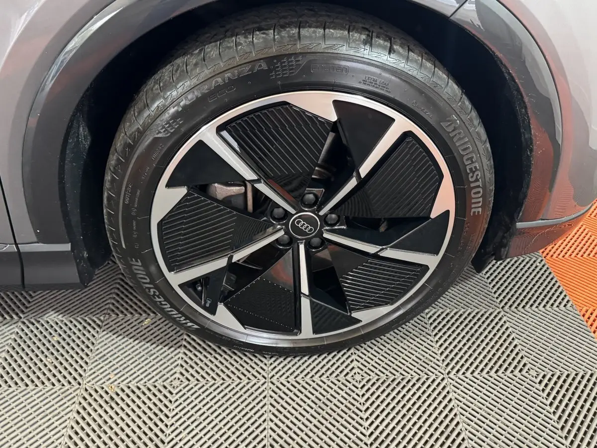 Gros plan sur la roue avant gauche gris foncé de l'Audi Q4 E-TRON 50 quattro avec jante noire et argentée design moderne.