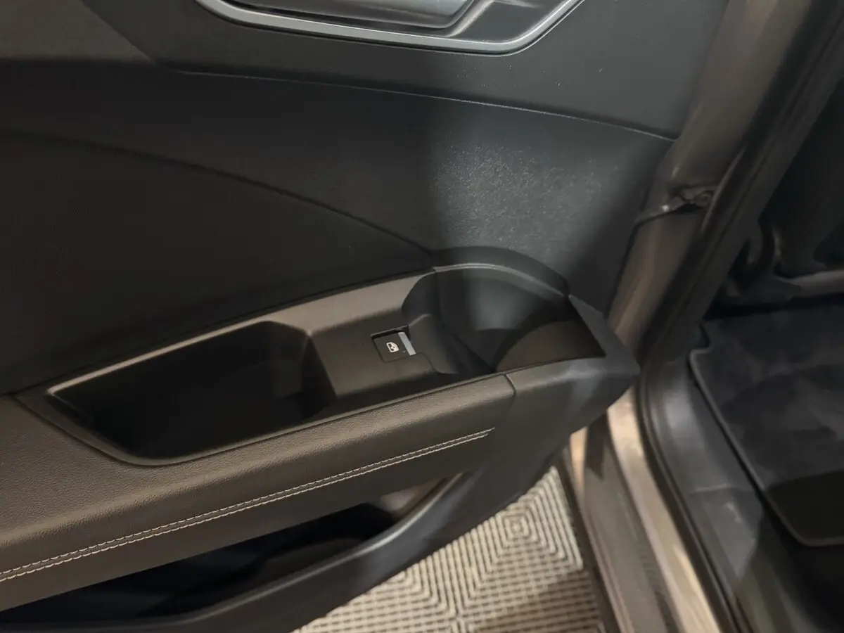 Gros plan sur la poignée intérieure et le bouton de verrouillage de la porte côté conducteur d'un Audi Q4 E-TRON gris foncé.