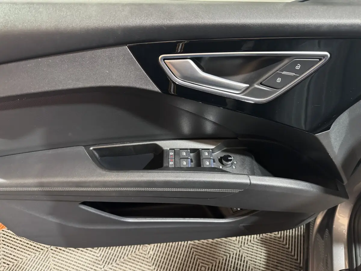 Poignée de porte intérieure côté gauche noire avec commandes de vitres et verrouillage sur Audi Q4 E-TRON gris foncé.