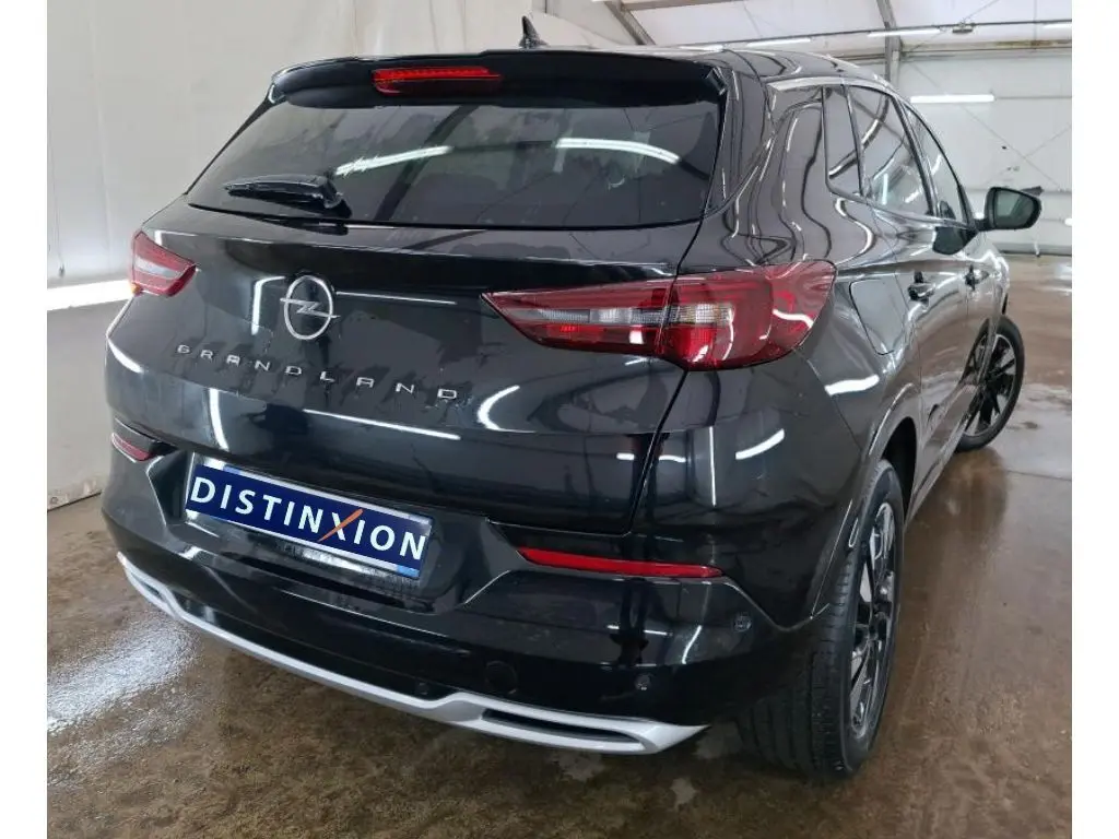 Vue 3/4 arrière droite d'un Opel Grandland noir 2023 avec feux arrière LED et jantes alliage foncé.
