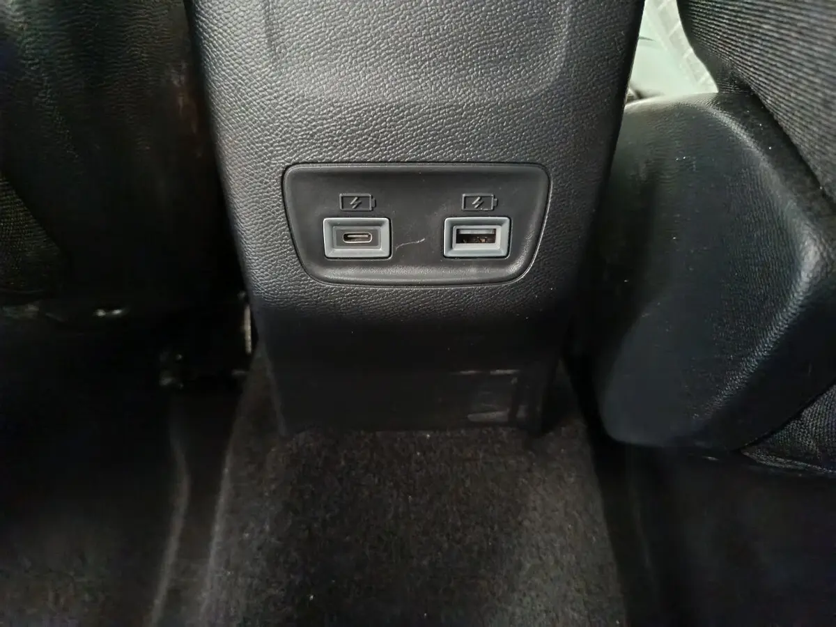 Prise USB-C et USB-A pour recharge à l'arrière d'une Peugeot 208 gris clair, vue centrée en intérieur.