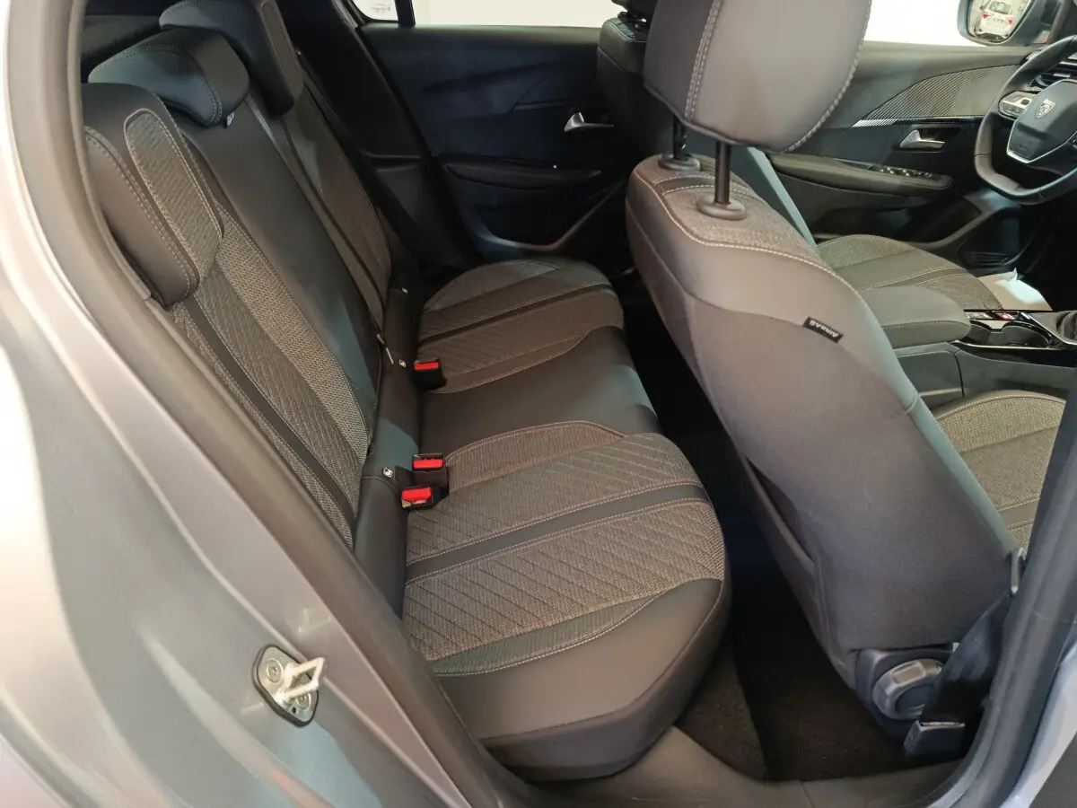 Vue intérieure côté arrière gauche de la Peugeot 208 gris clair, montrant la banquette arrière et partie des sièges avant.