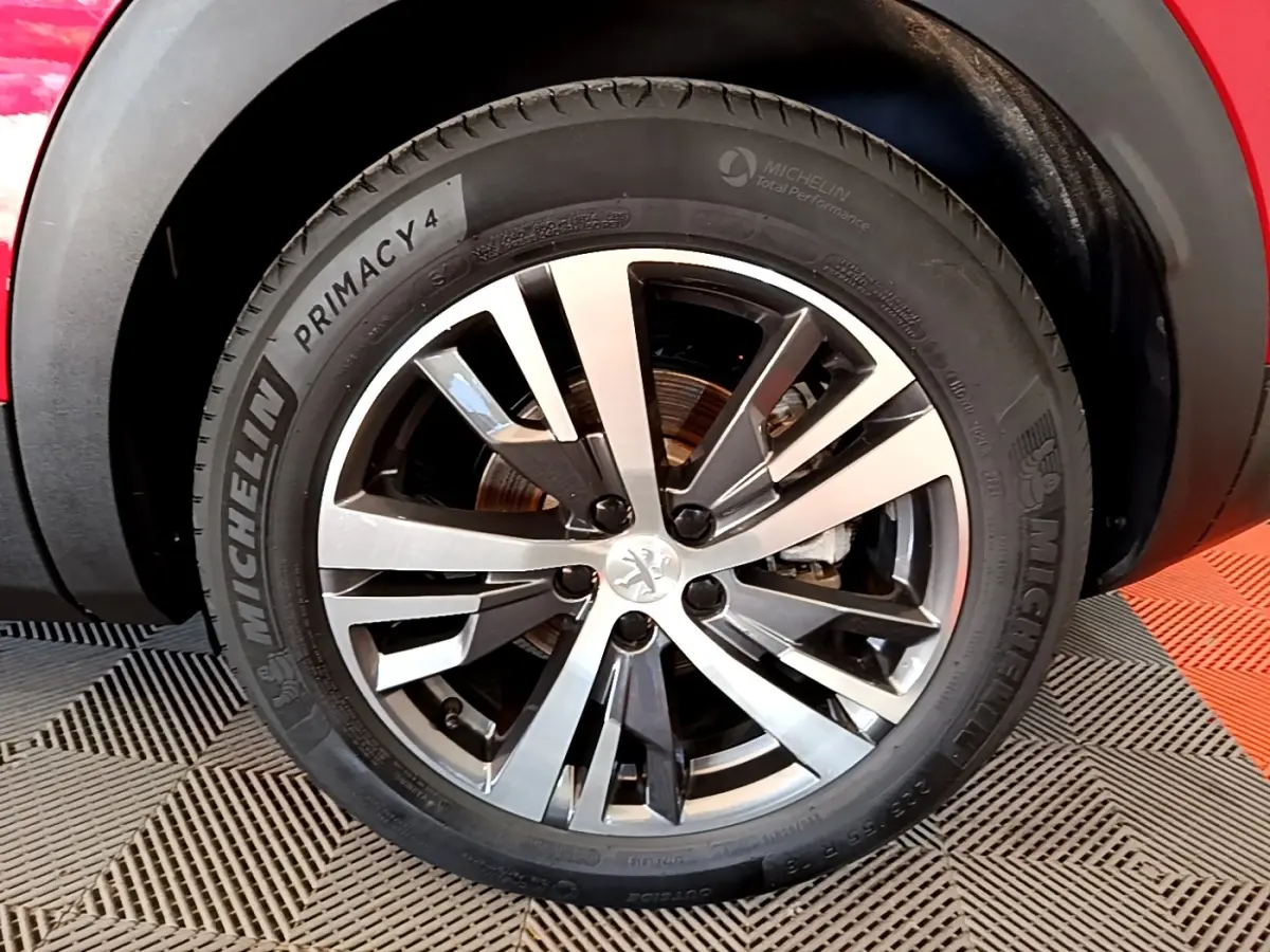 Gros plan sur la roue avant droite du Peugeot 3008 hybride rechargeable rouge, avec jante alliage et pneu Michelin.