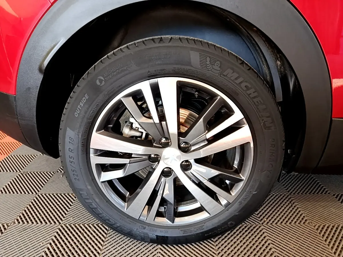 Gros plan sur la roue avant droite du Peugeot 3008 hybride rechargeable rouge avec jante alliage à design moderne.