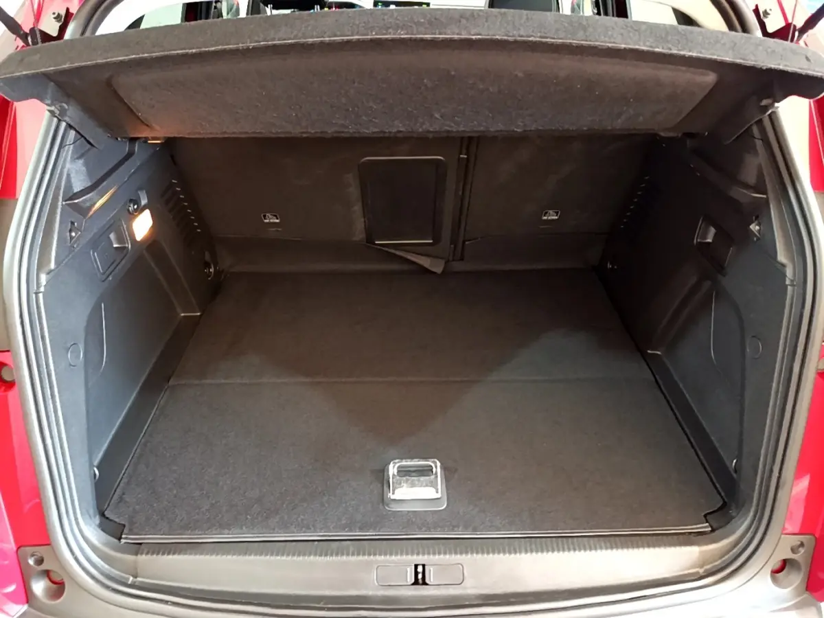 Coffre ouvert rouge du Peugeot 3008 1.6 Hybrid 225, vue arrière montrant l’espace de chargement vide et tapis noir.